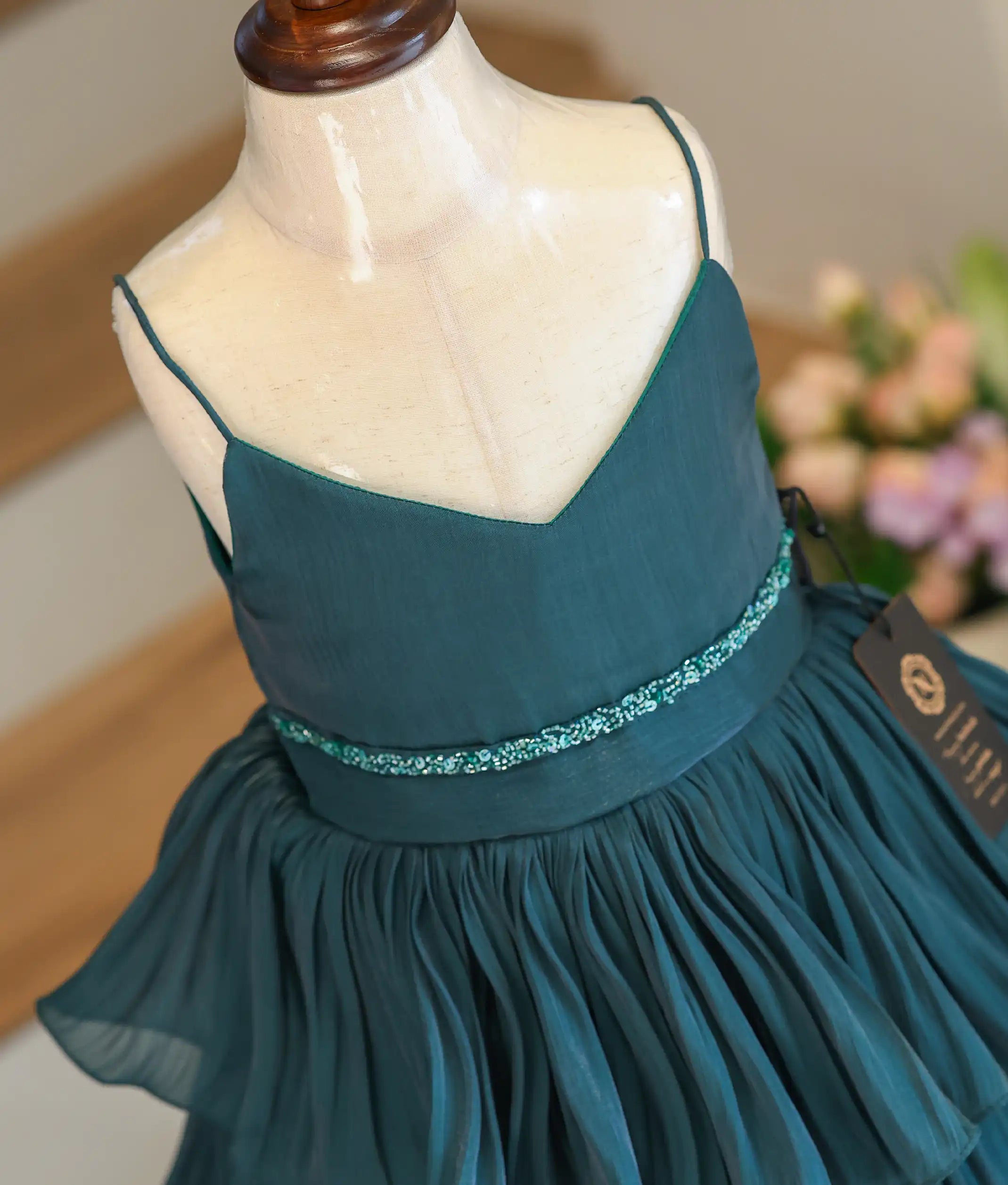 A close-up shot of the green frock showing the unique shimmering texture of the laser organza fabric and the hand-worked waistline.