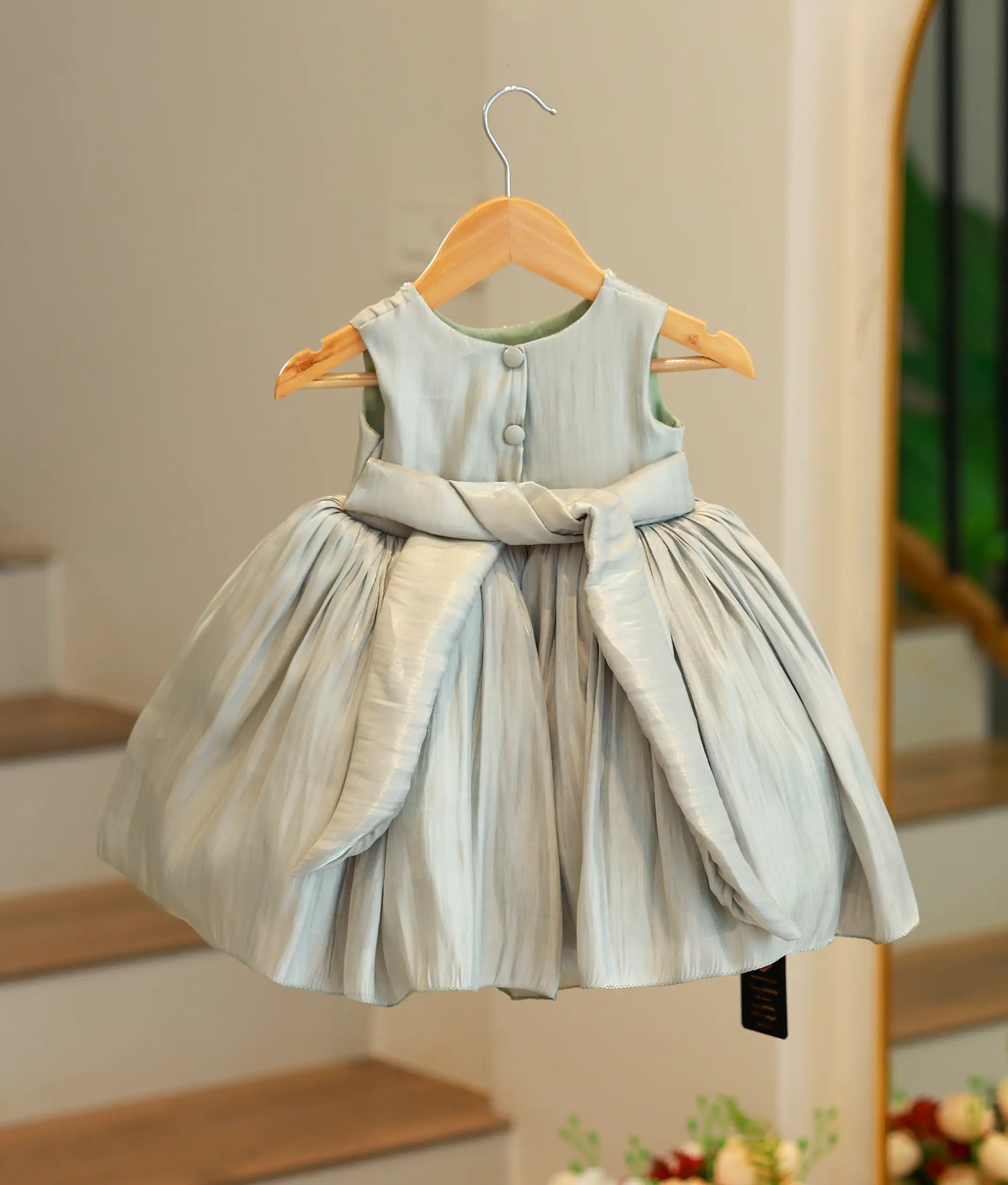 Back view of the green birthday frock showing the round neck design, back button closures, and a matching green tulle tie tied into a bow.