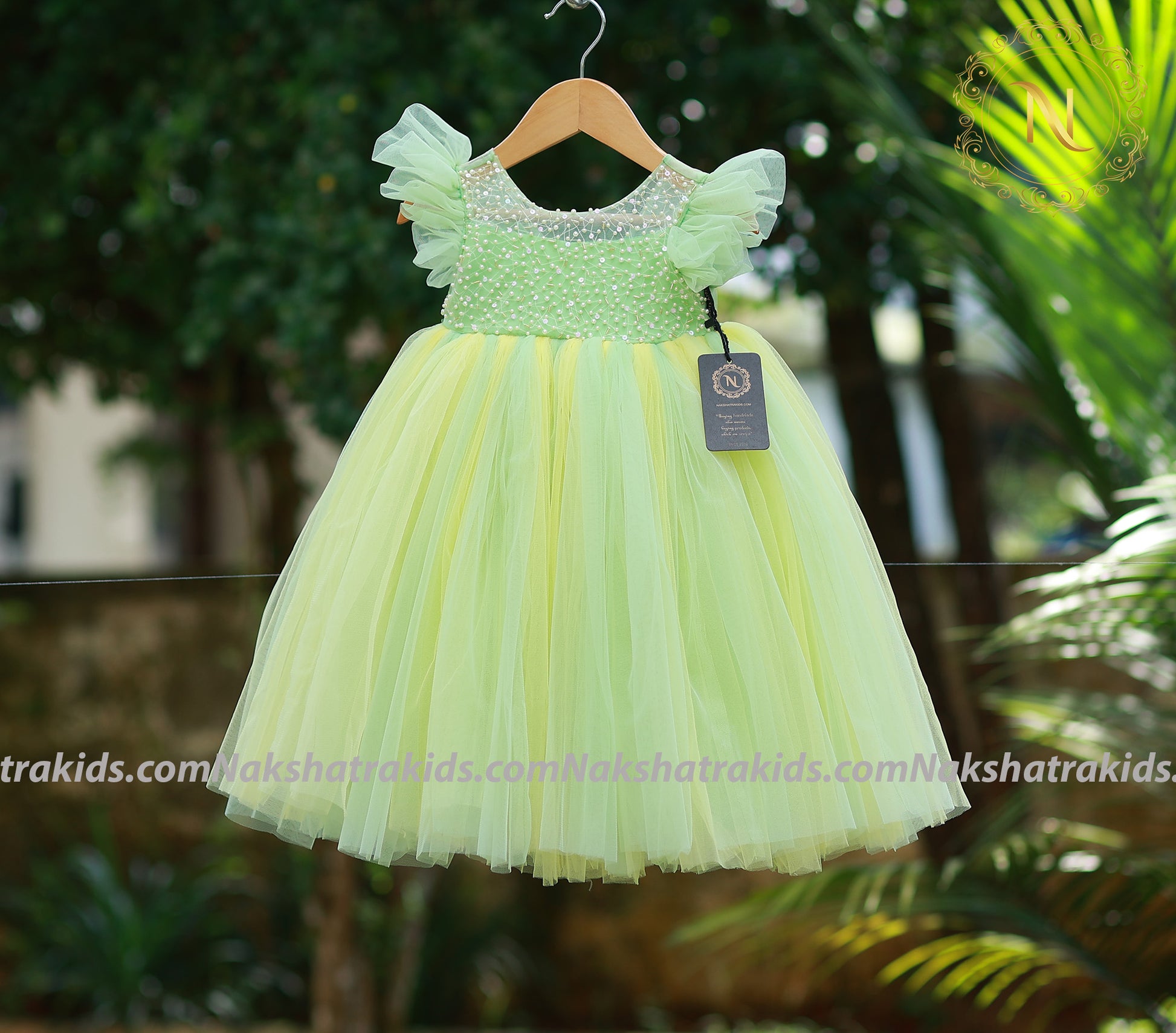 Front view of a full-length green and yellow layered tulle net birthday gown for baby girls.