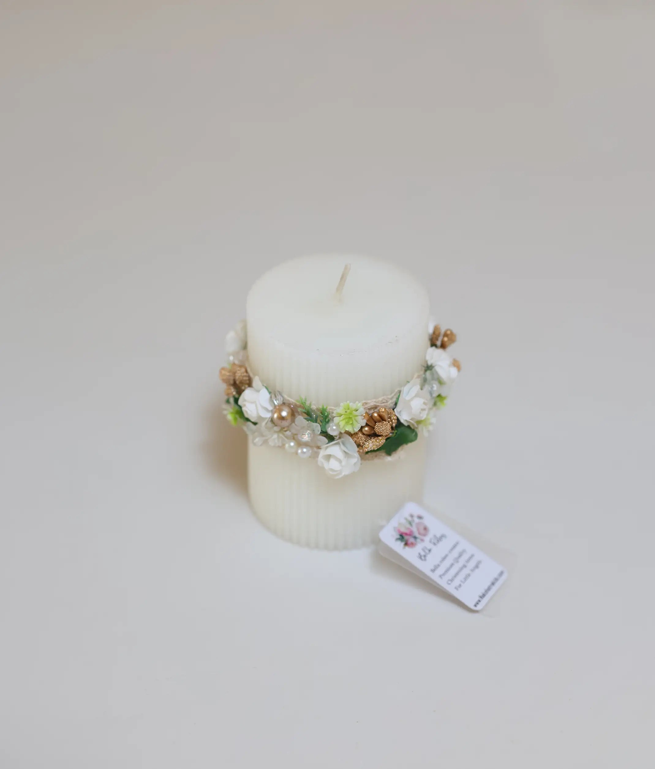 Close-up of the intricate floral handwork and lace ruffles on a premium white christening pillar candle
