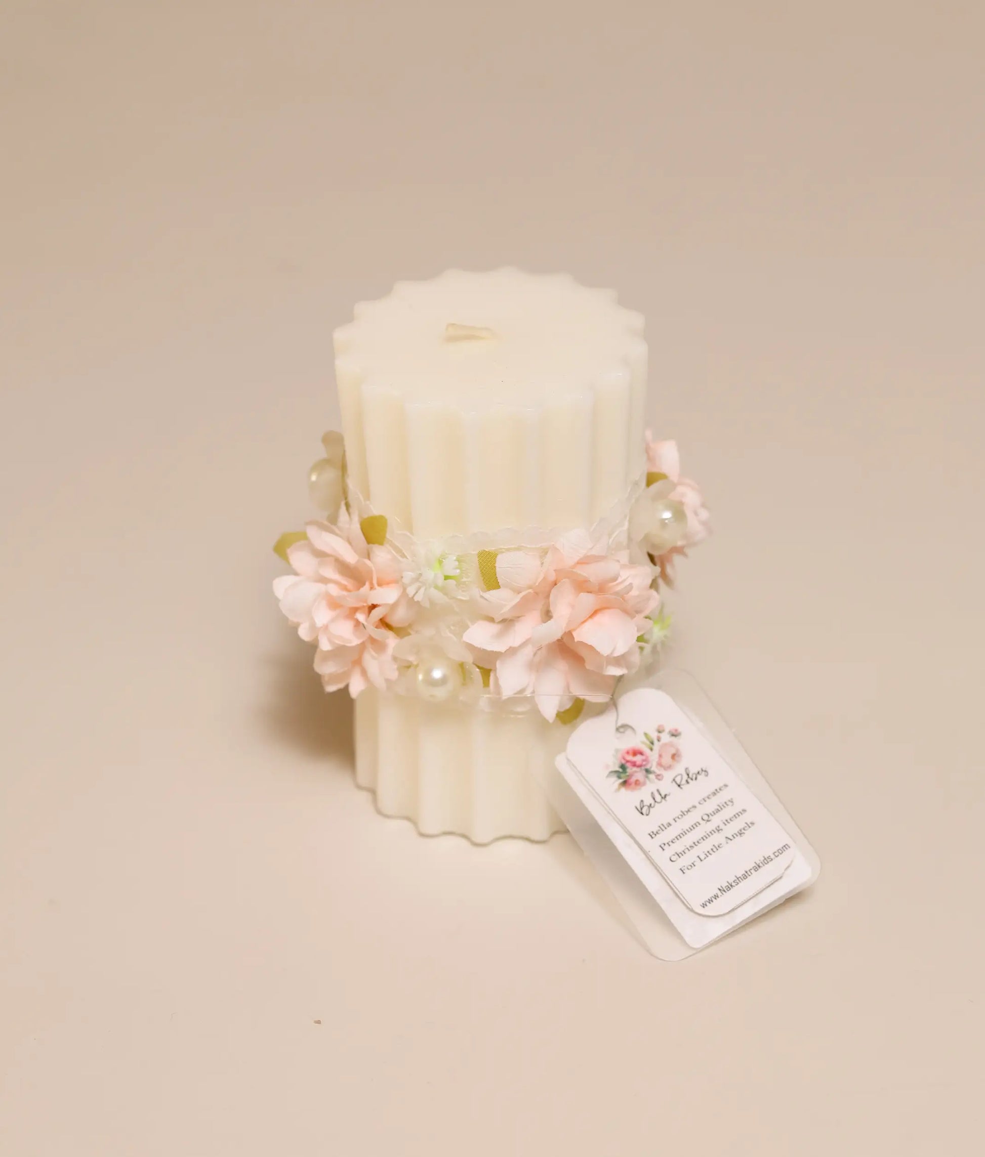 Close-up of handcrafted peach floral decor and intricate lace trim on a white christening ceremony candle