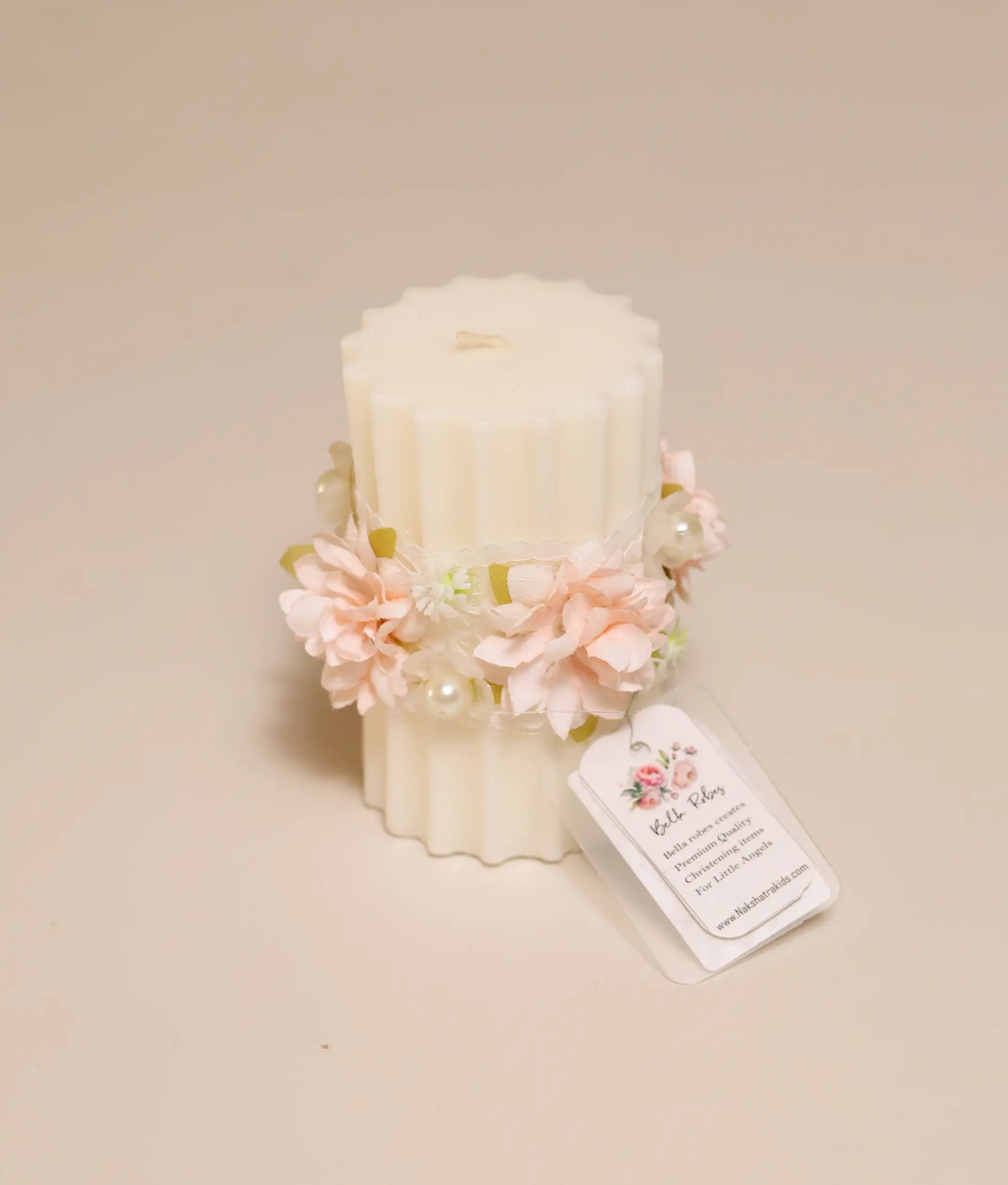 Close-up of handcrafted peach floral decor and intricate lace trim on a white christening ceremony candle