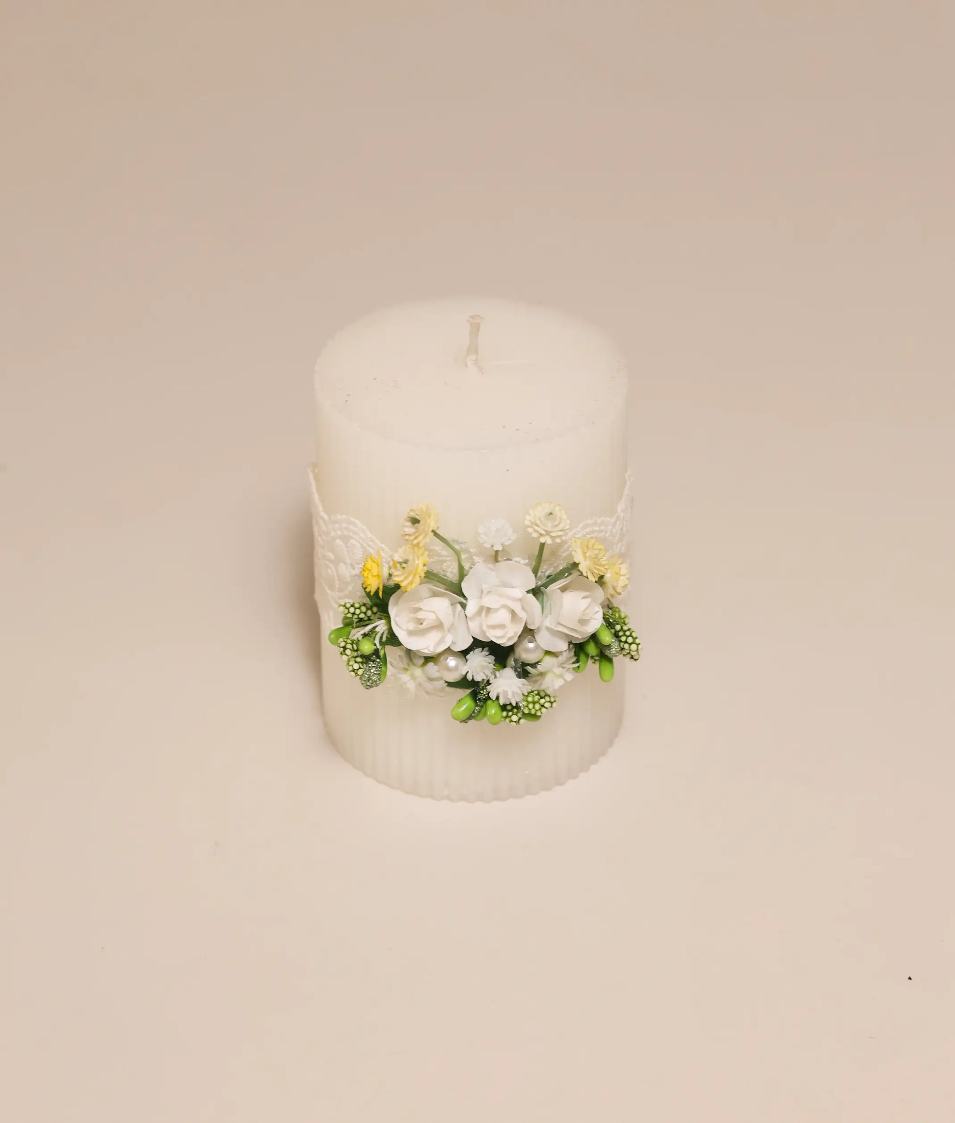 Close-up of handcrafted yellow floral embellishments and delicate lace on a premium christening ceremony candle
