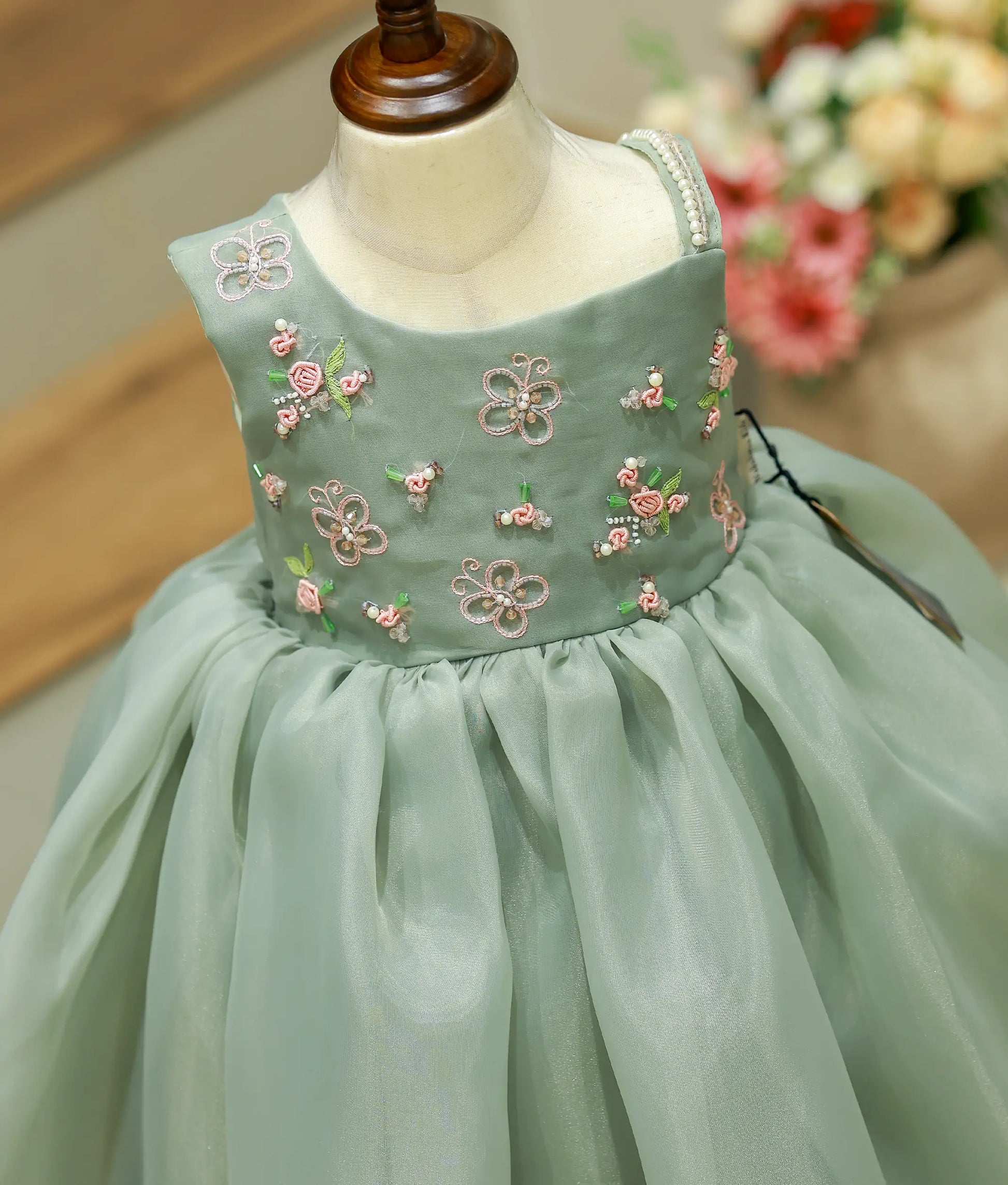 Close-up detailing of the intricate hand embroidery and premium satin organza fabric on green gown