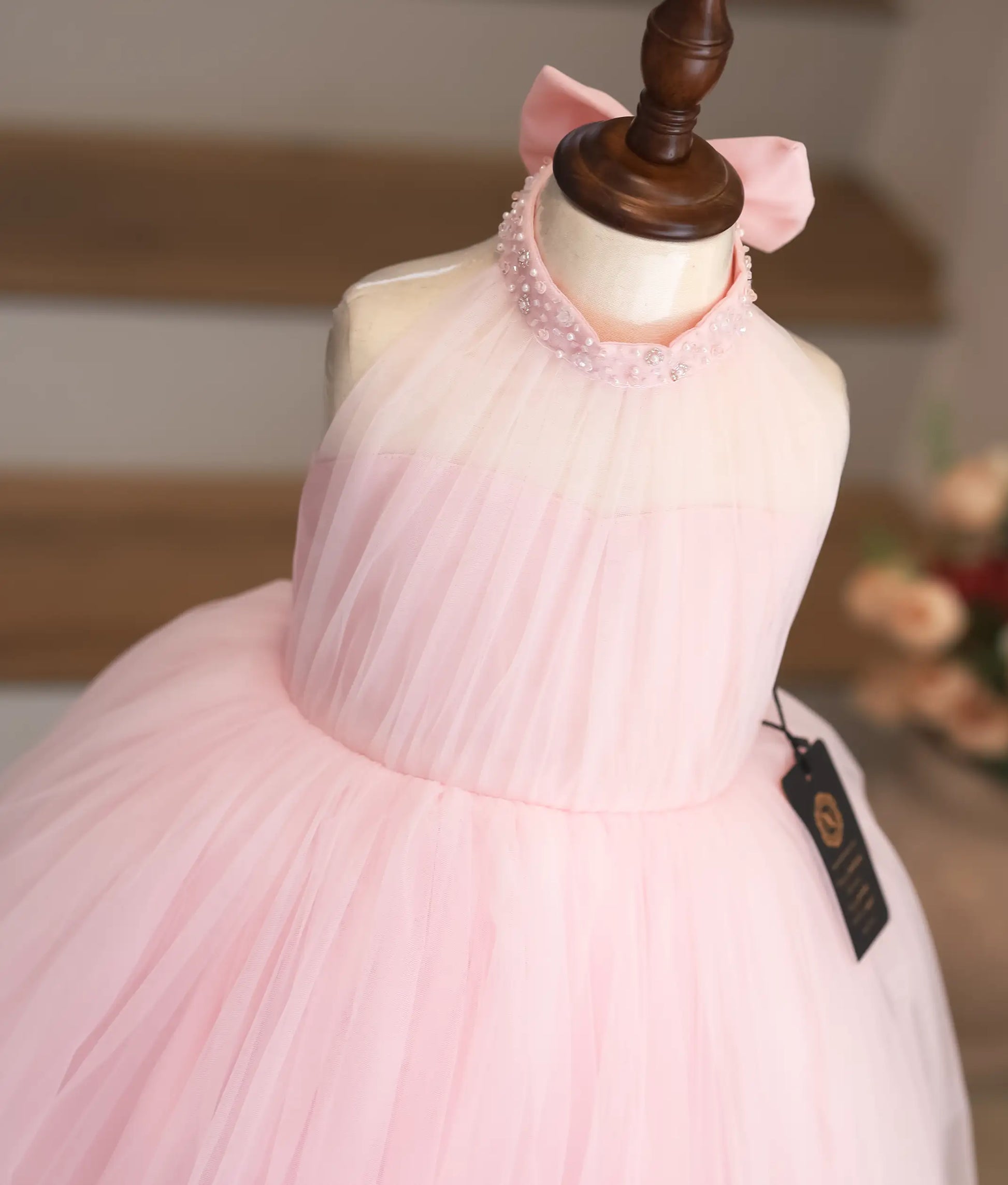 Close-up of the pearl and thread flower handwork on the transparent neckline of the pink gown.