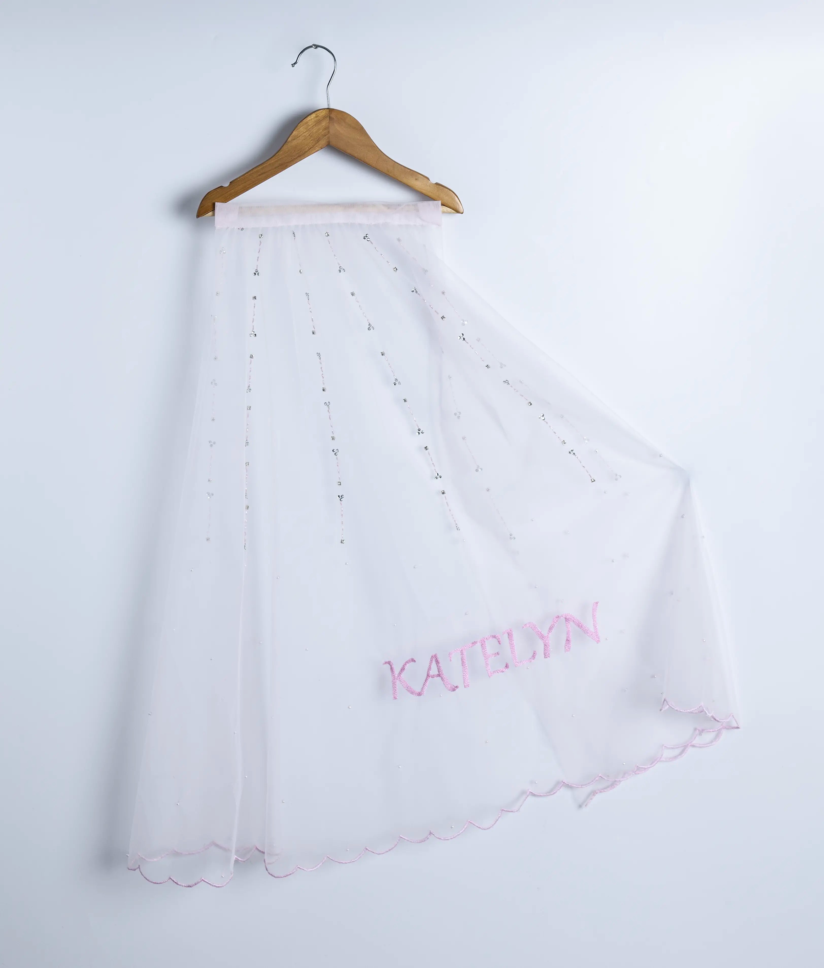 Close-up of the handworked tail showing intricate crystal, cut bead, and stone embellishments with scalloped edges