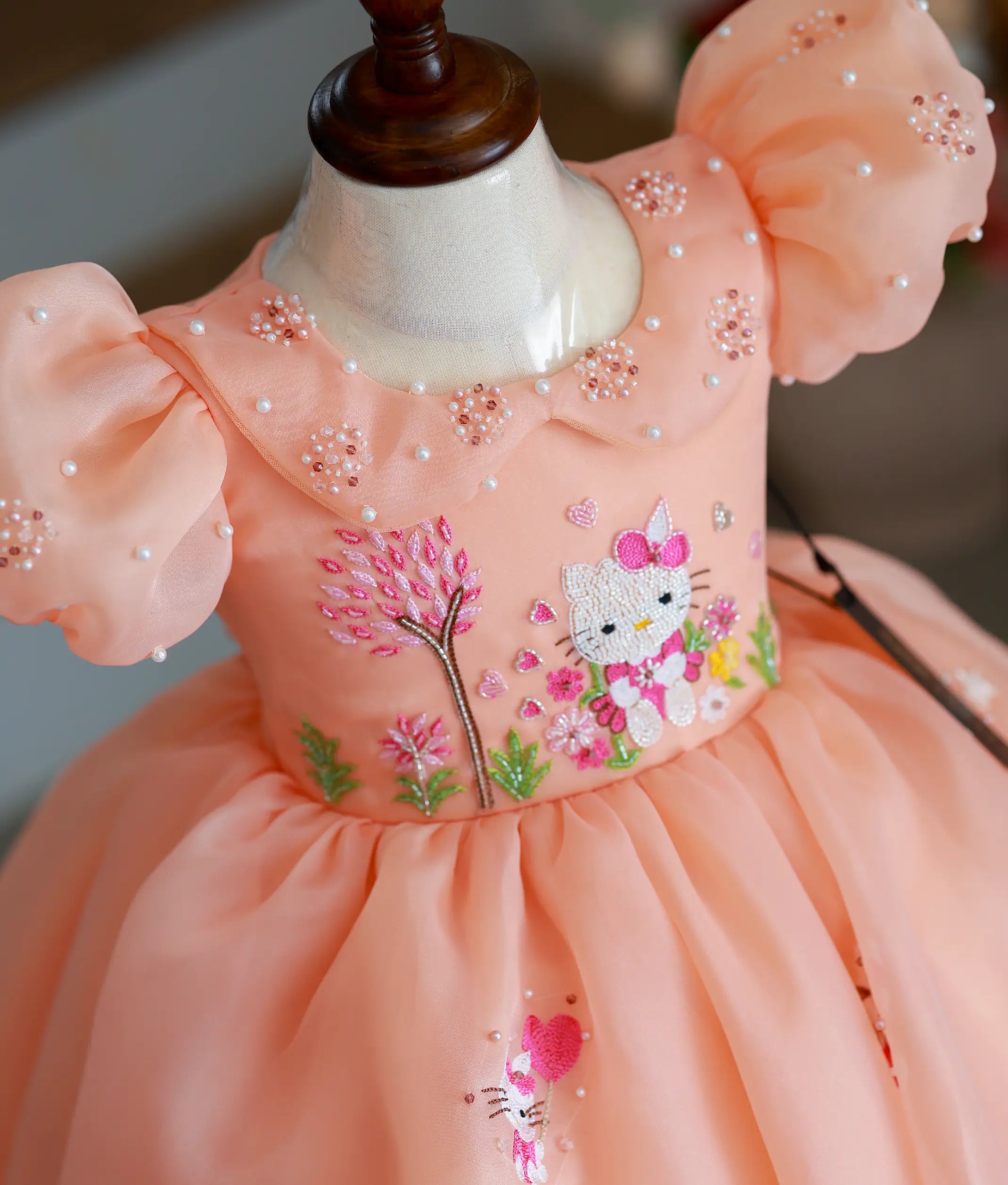 Close-up of the handworked Hello Kitty motif, beaded Peter Pan collar, and pearl-accented puff sleeves
