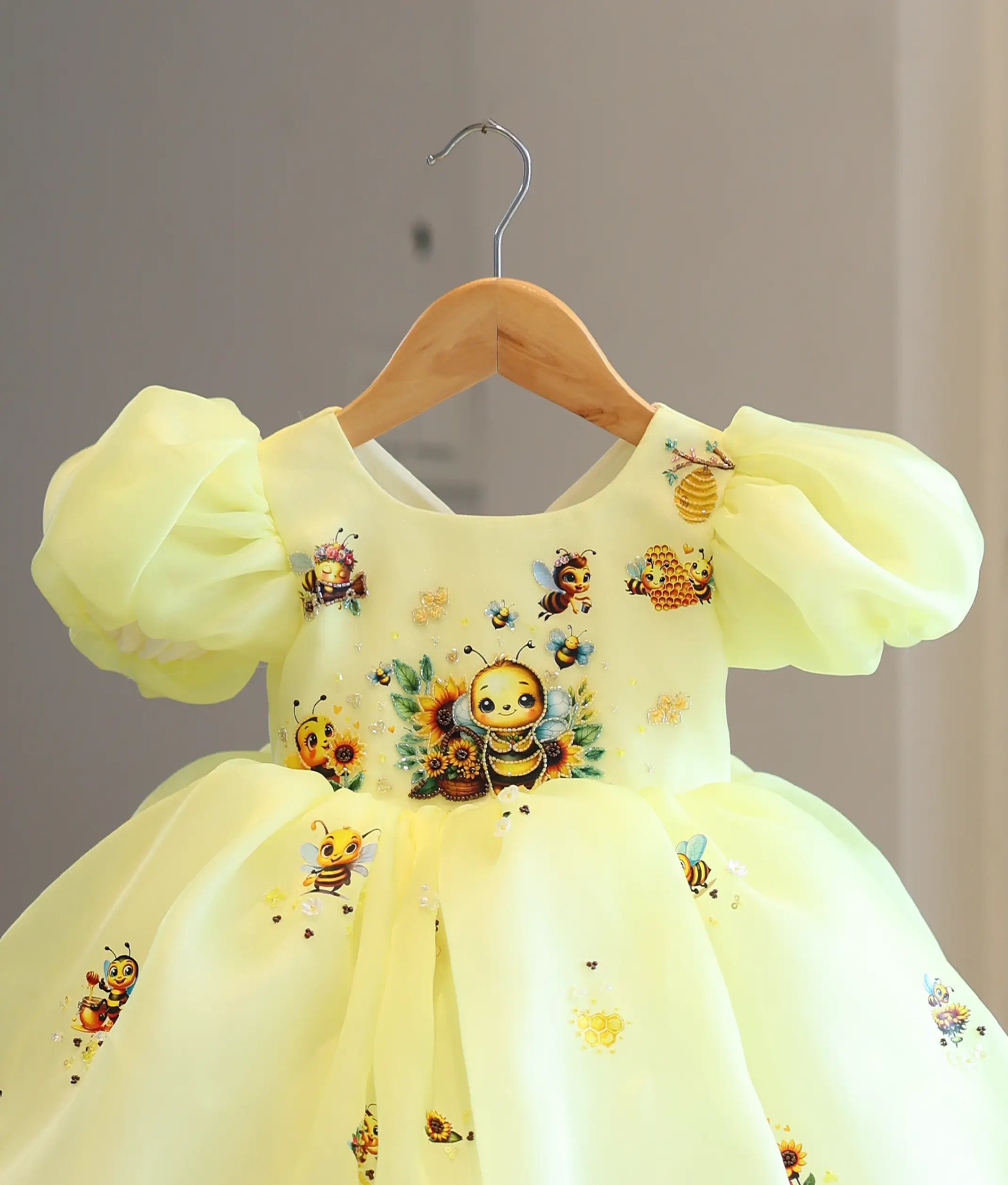 Close-up view of the yellow organza skirt panel showing a sweet printed honey bee carrying a honey pot, surrounded by hand-stitched sequins and a white 3D flower.