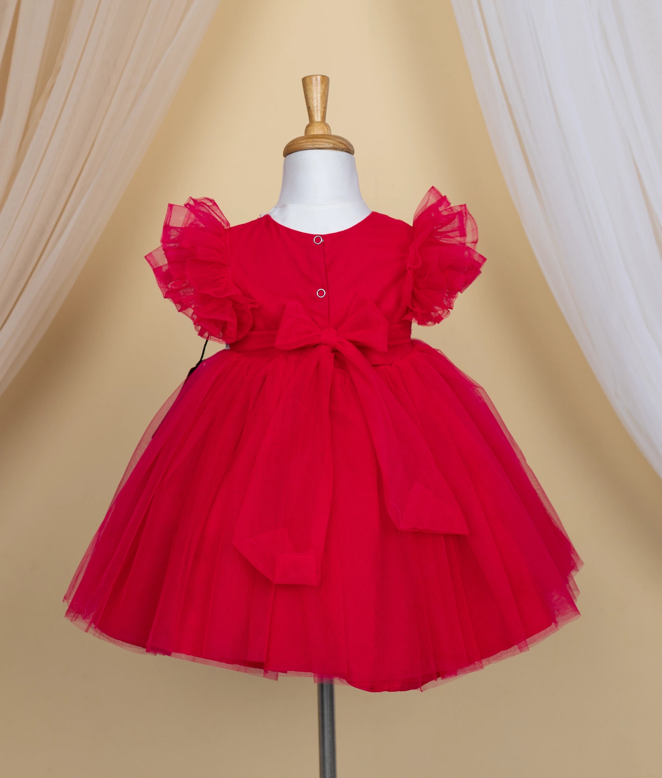 Back view of the hot pink frock showing the round neck, press button closure, and the back tie.