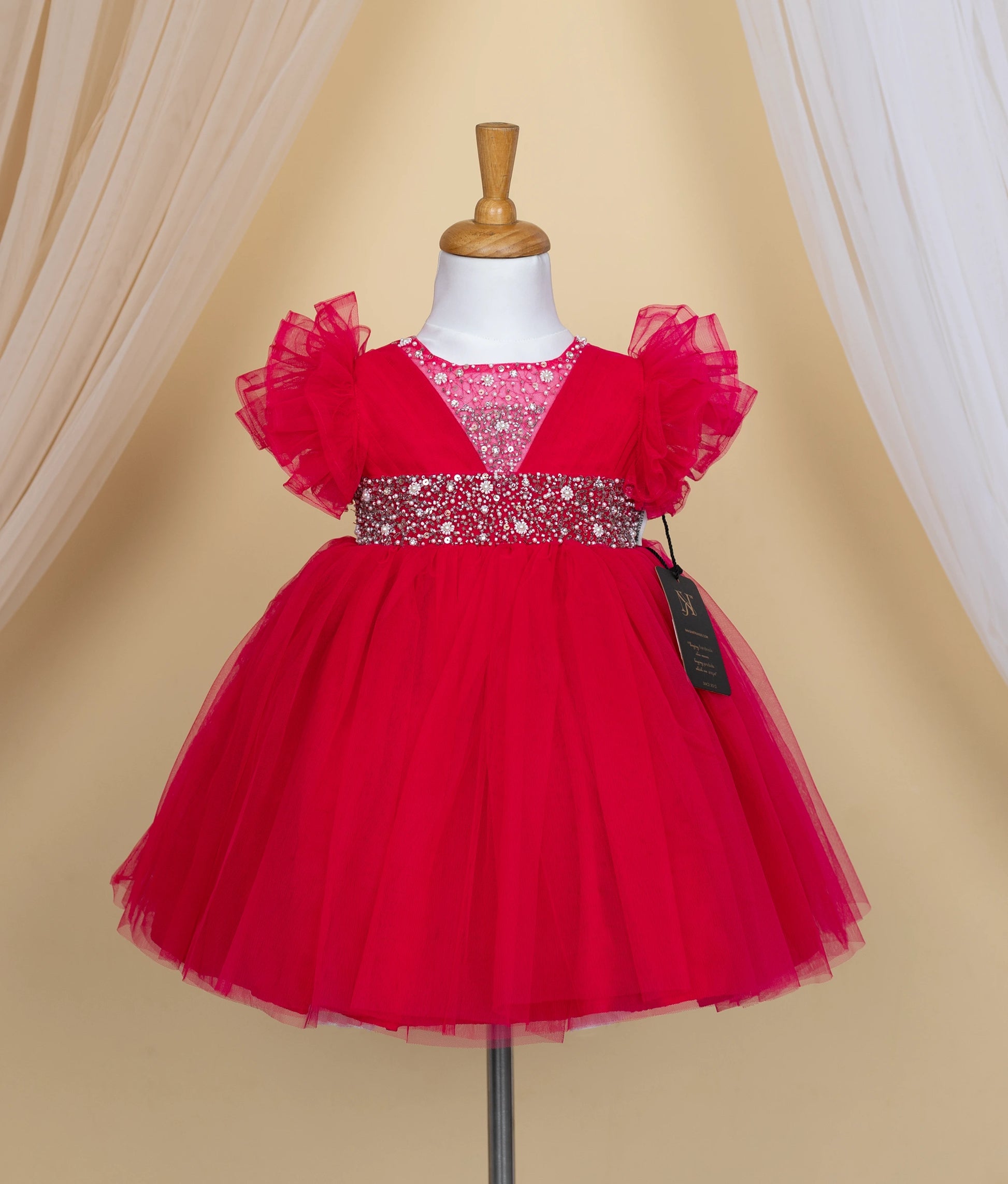 Front view of a hot pink tulle net birthday frock featuring a sequin and pearl decorated bodice.