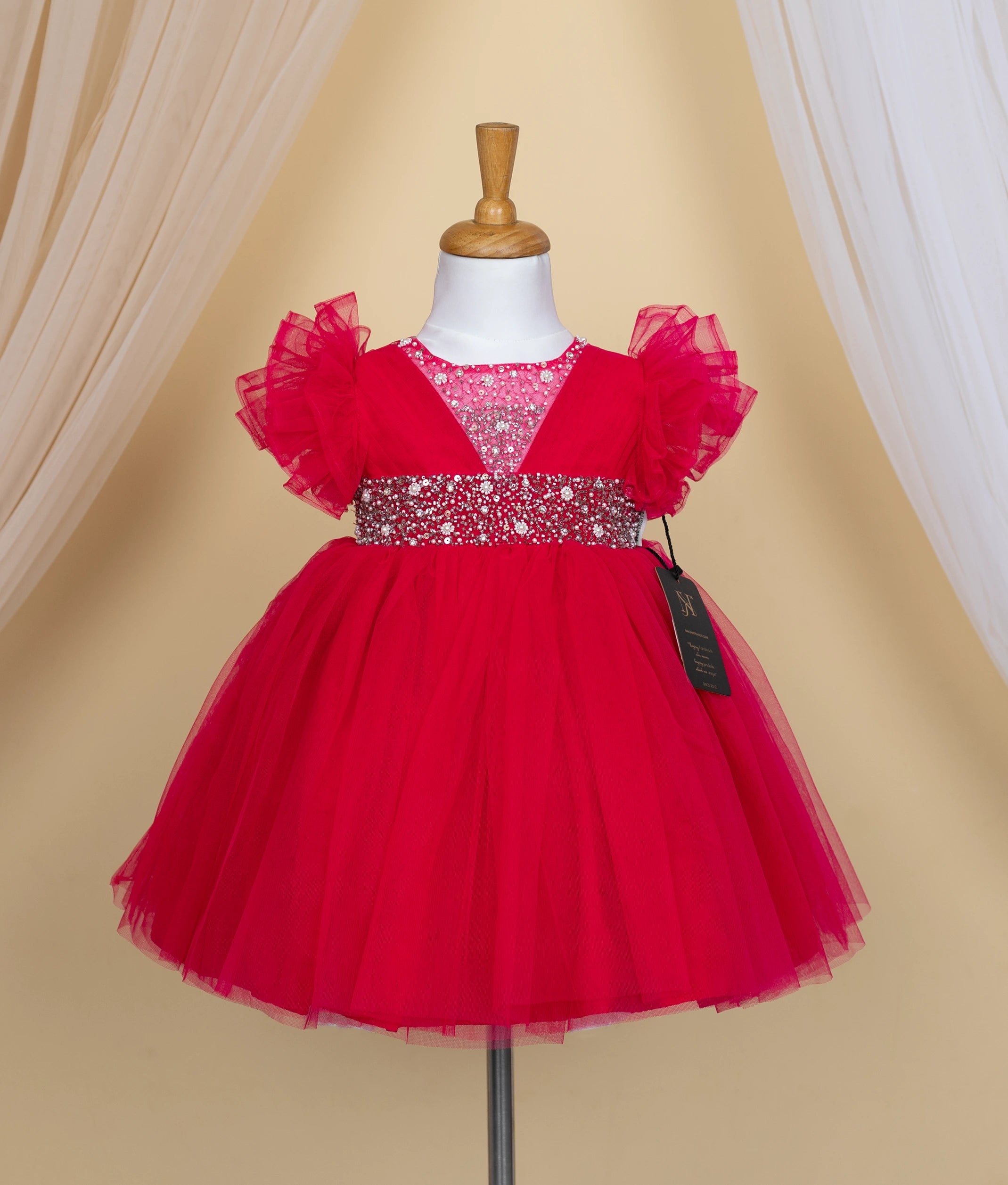 Front view of a hot pink tulle net birthday frock featuring a sequin and pearl decorated bodice.