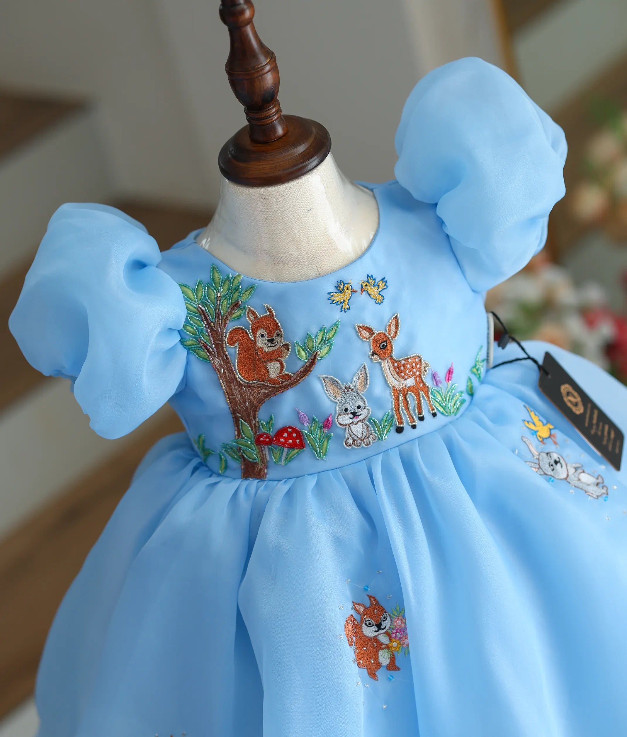 Close-up of the squirrel and deer handwork made with beads and threads on the blue bodice.