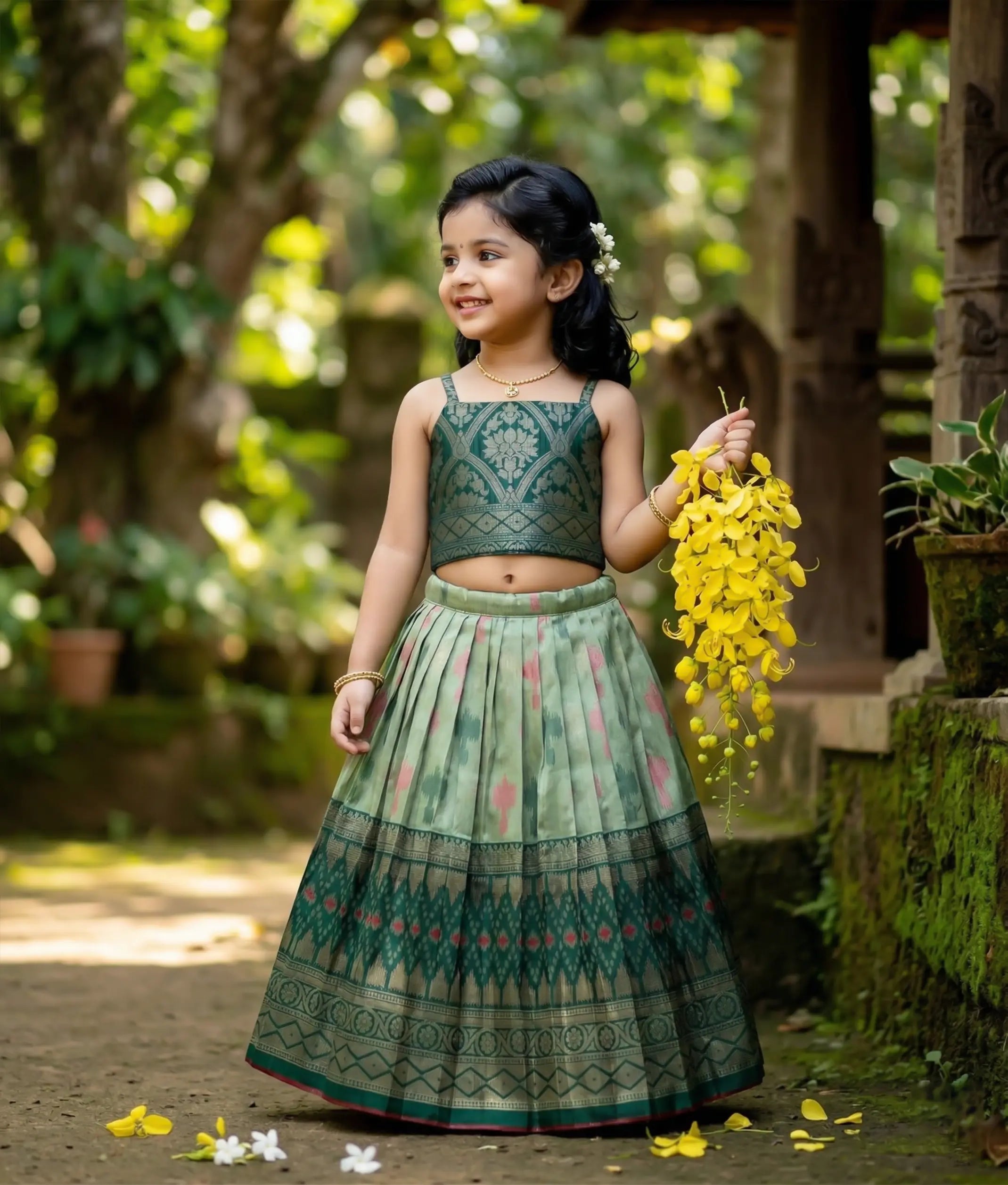 Baby girl wearing a traditional kanchipuram silk emerald green top and a pastel green skirt with zari patterns.