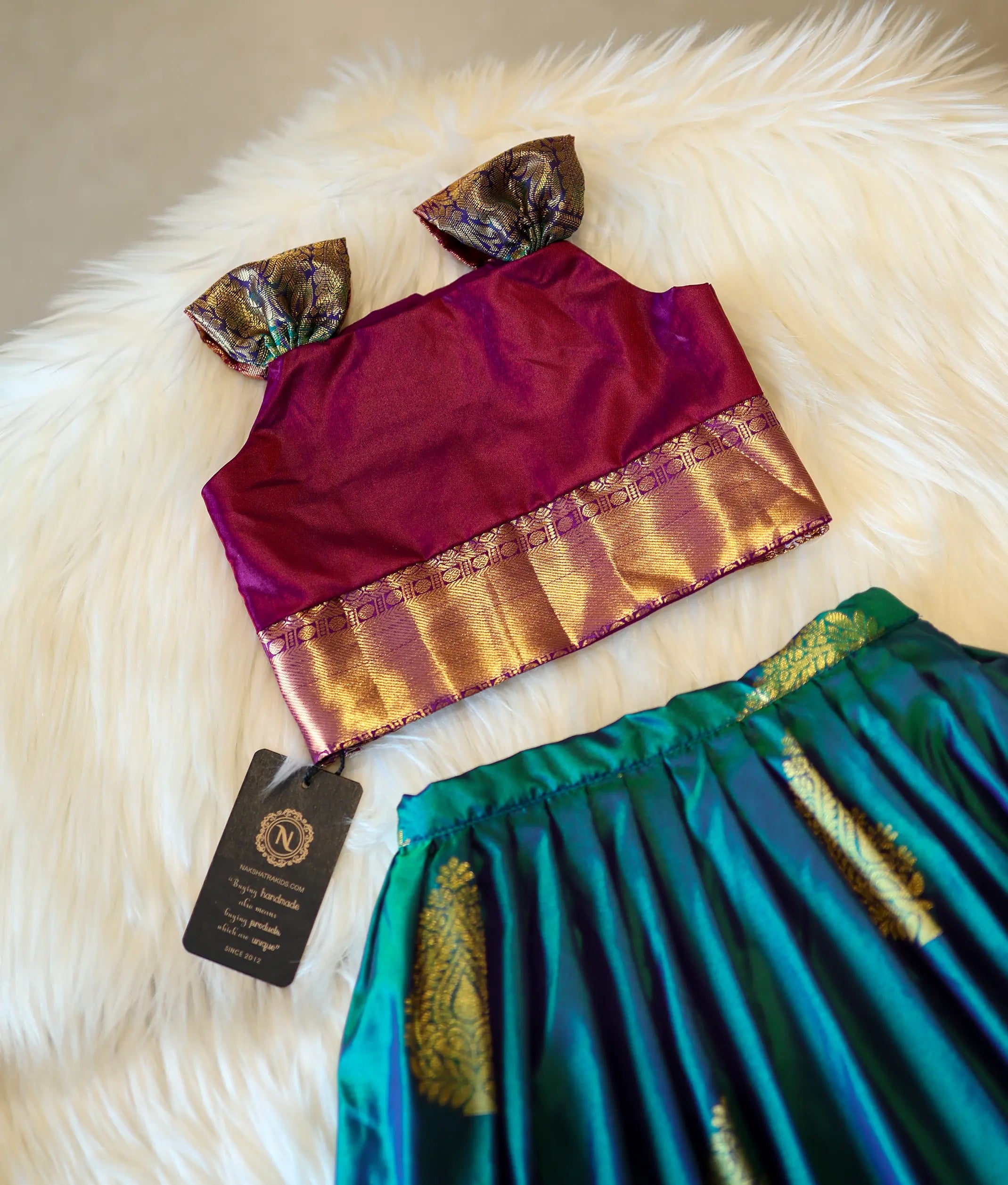 Detailed view of the golden zari weaving and floral patterns on the magenta Kanchipuram silk top.