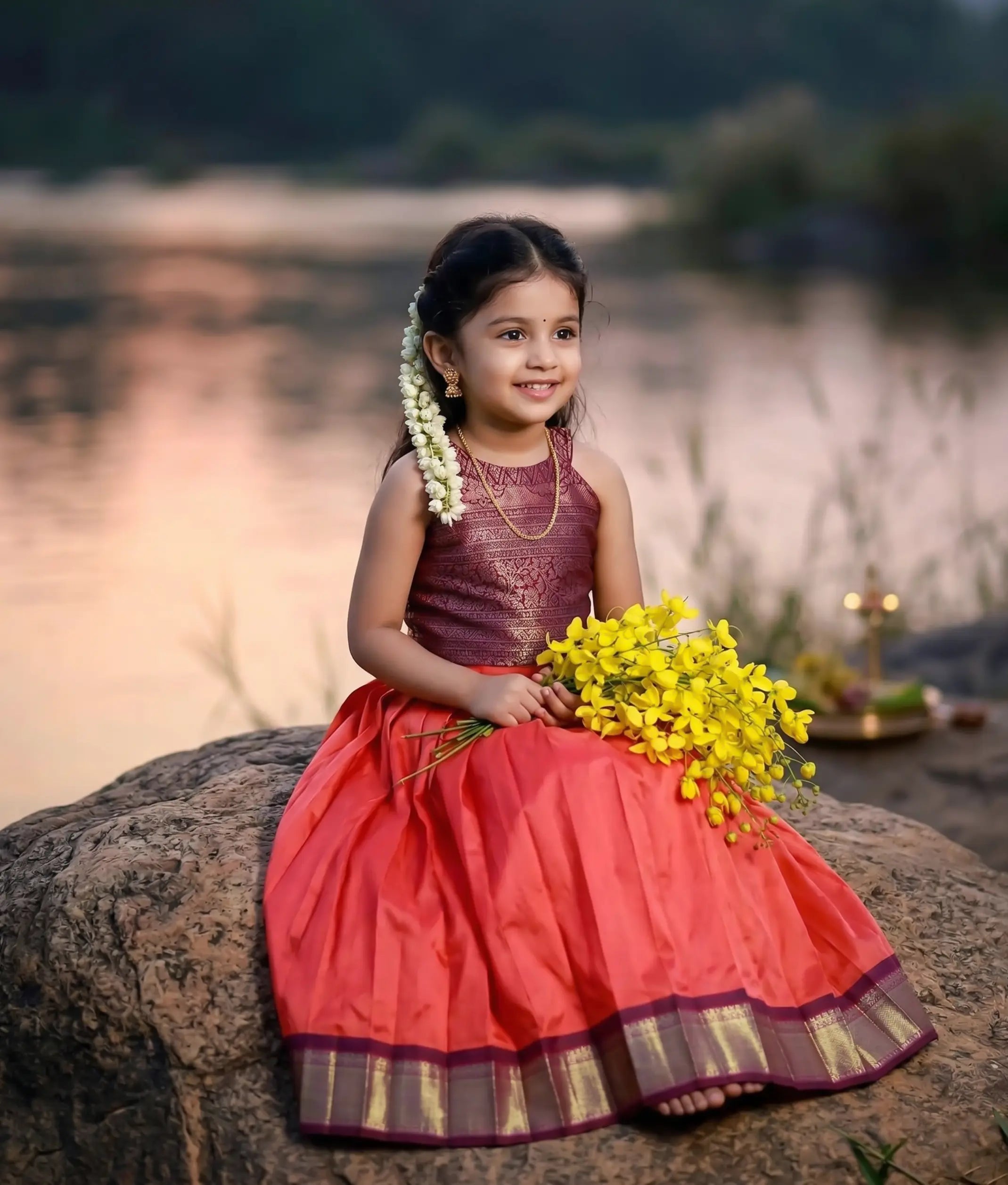 Baby girl wearing a traditional kanchipuram silk skirt and top in magenta and red colors.