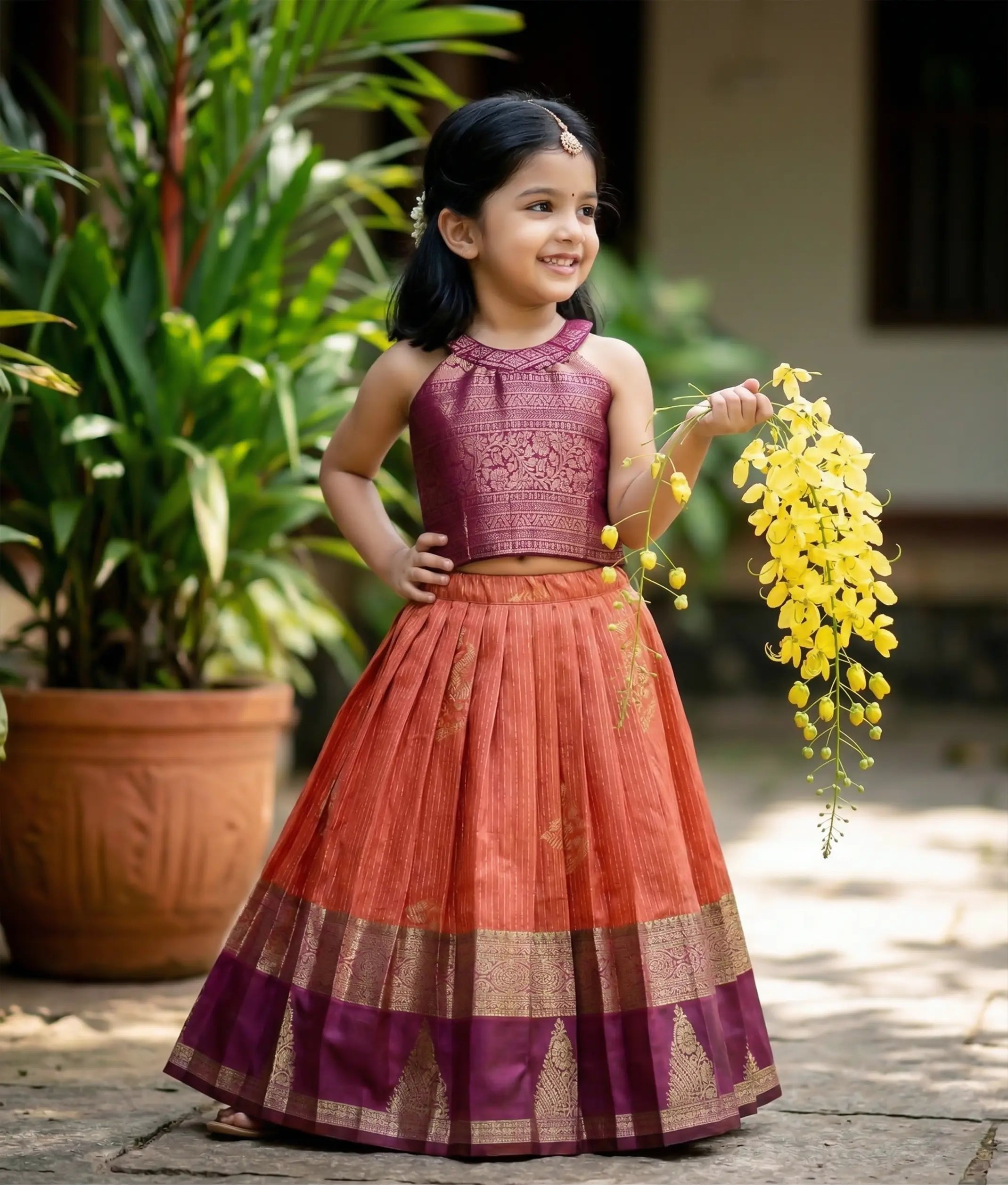 Baby girl wearing a traditional kanchipuram silk skirt and top in red and magenta colors.