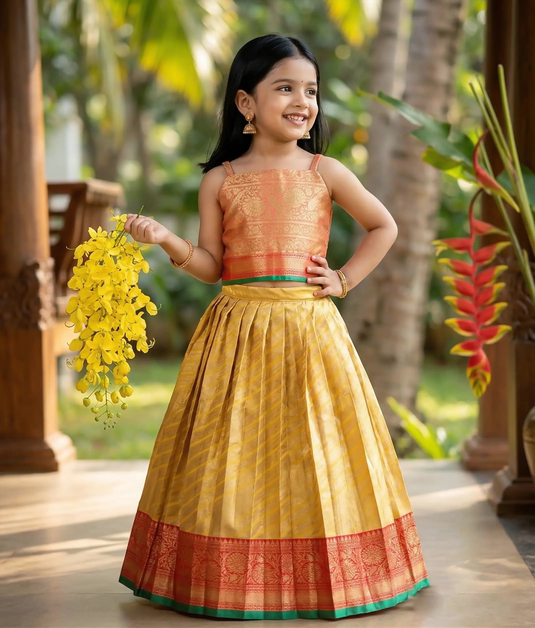 Baby girl wearing a traditional zari-patterned orange top and a mustard yellow frock in Kanchipuram silk.