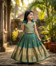 Baby girl wearing an ethnic emerald green skirt and top with a zari pattern in kanchipuram silk.