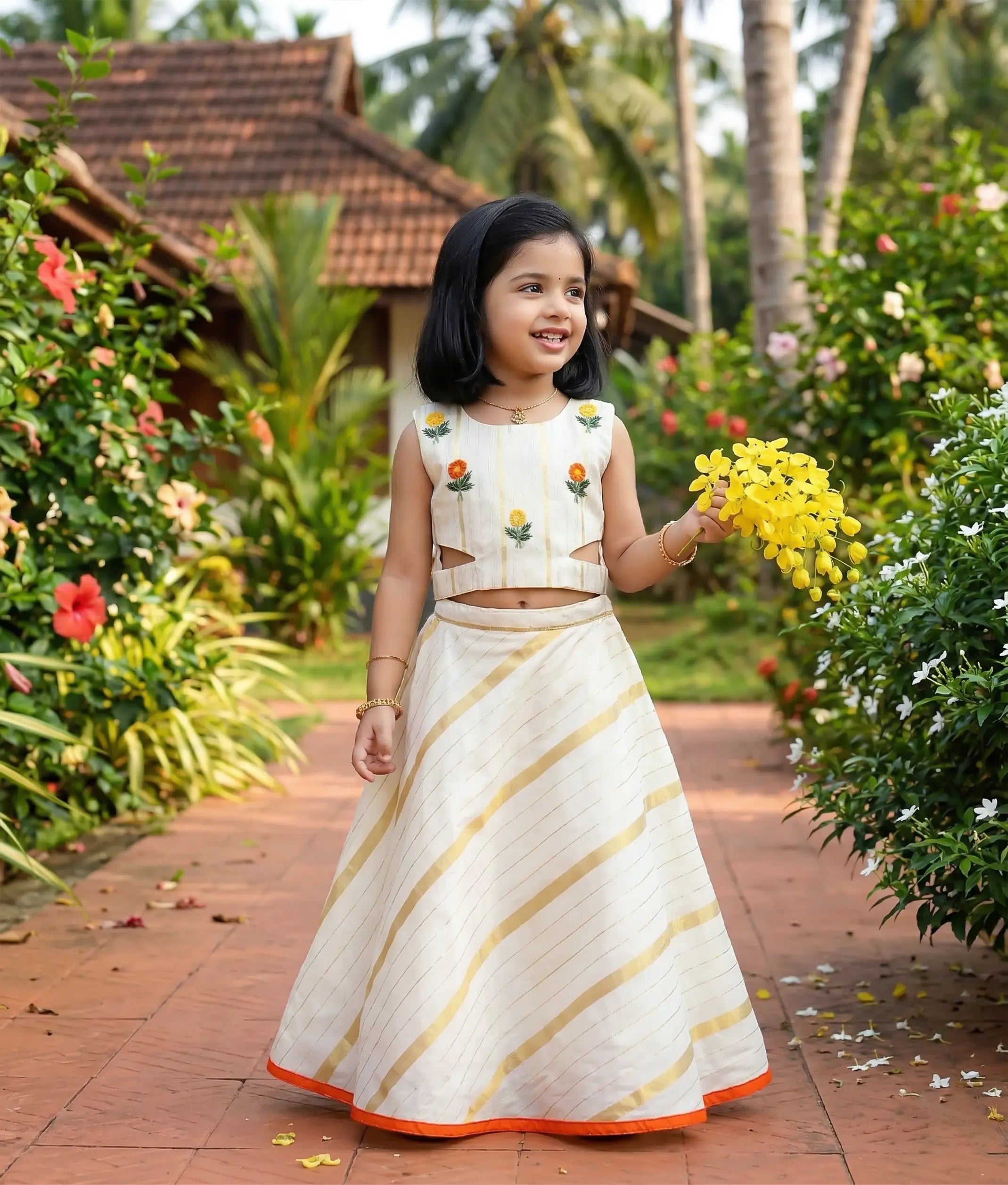 Baby girl wearing an ethnic kasavu skirt and top with floral embroidery. 