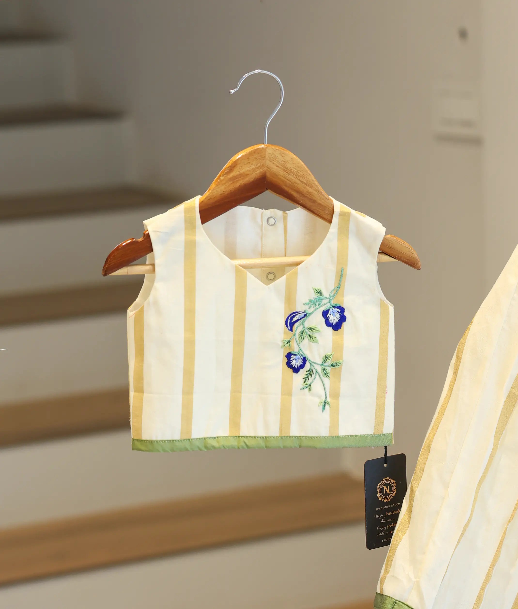 Close-up of the blue floral embroidery and golden stripe patterns on the Kasavu skirt and top.