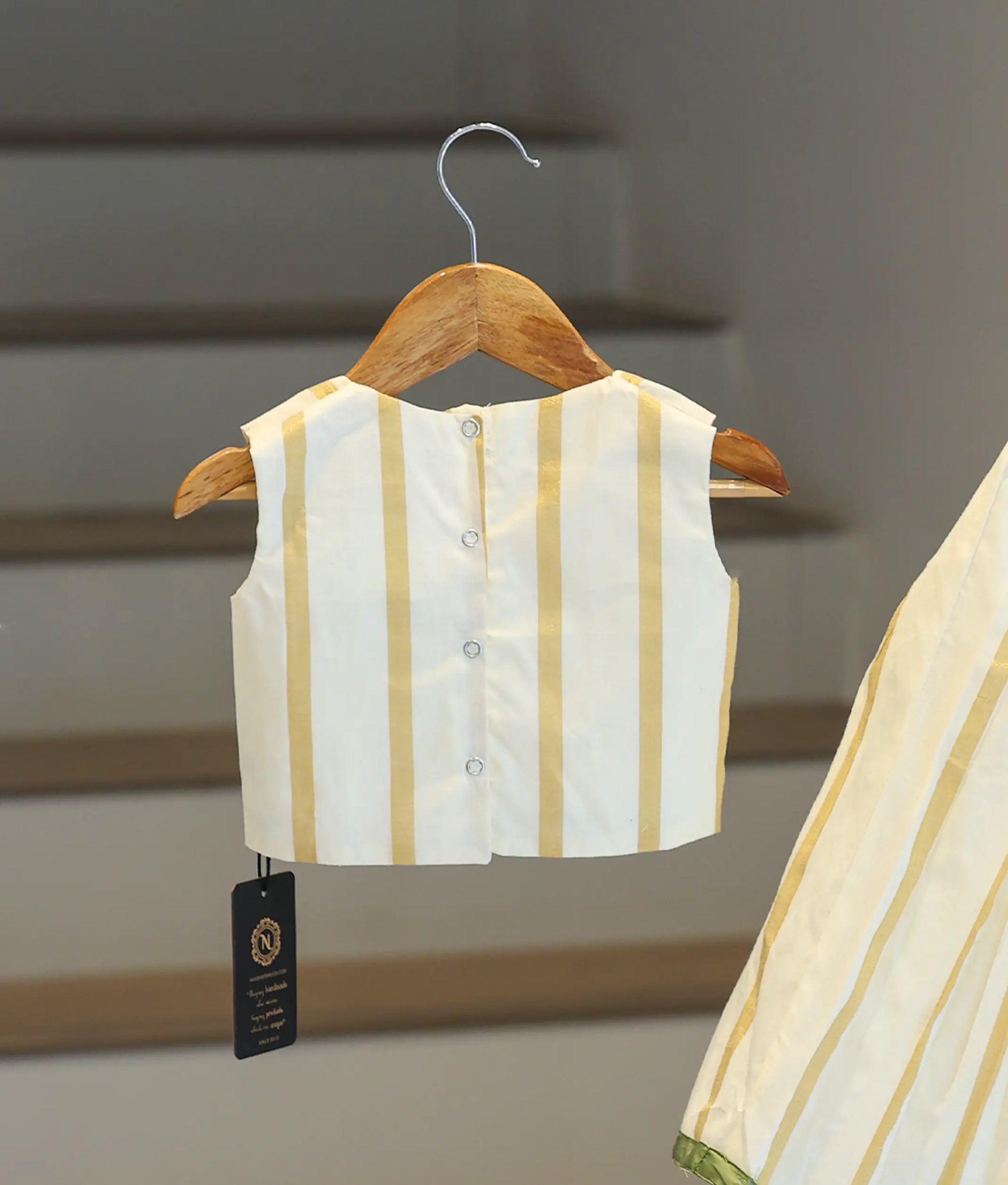 Back view of the Kasavu skirt and top showing the button closures and pleated fabric design.