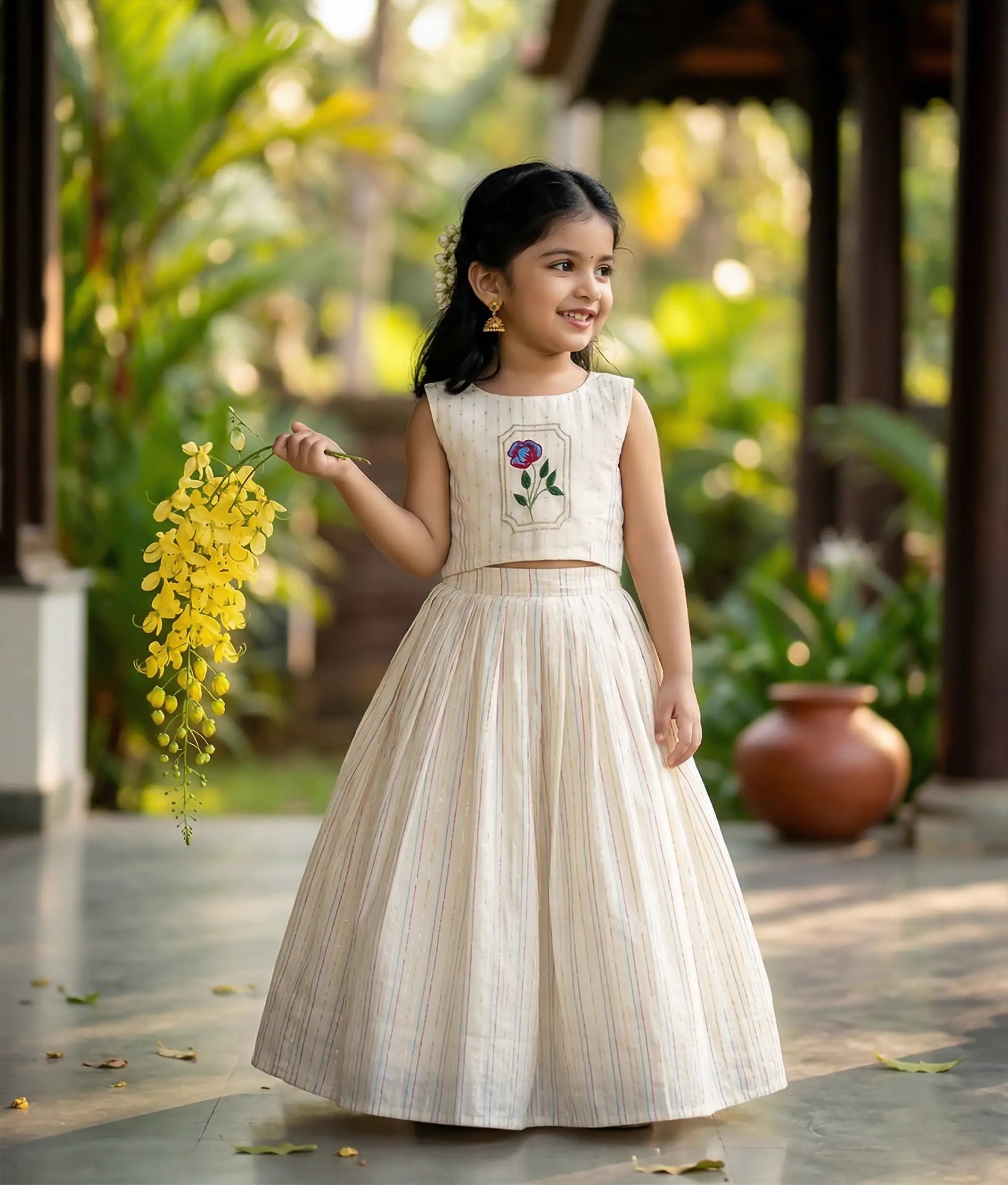 Baby girl wearing an ethnic off-white skirt and top with floral embroidery on the yoke.