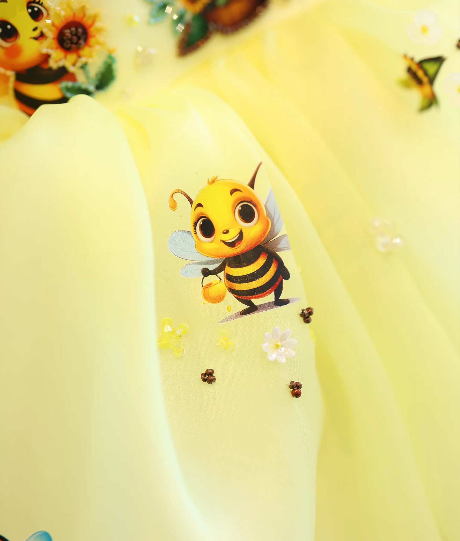 Detailed close-up view of the dress top, highlighting the printed honey bee scene intricately accented with handworked glass beads, sequins, and honeycombs.