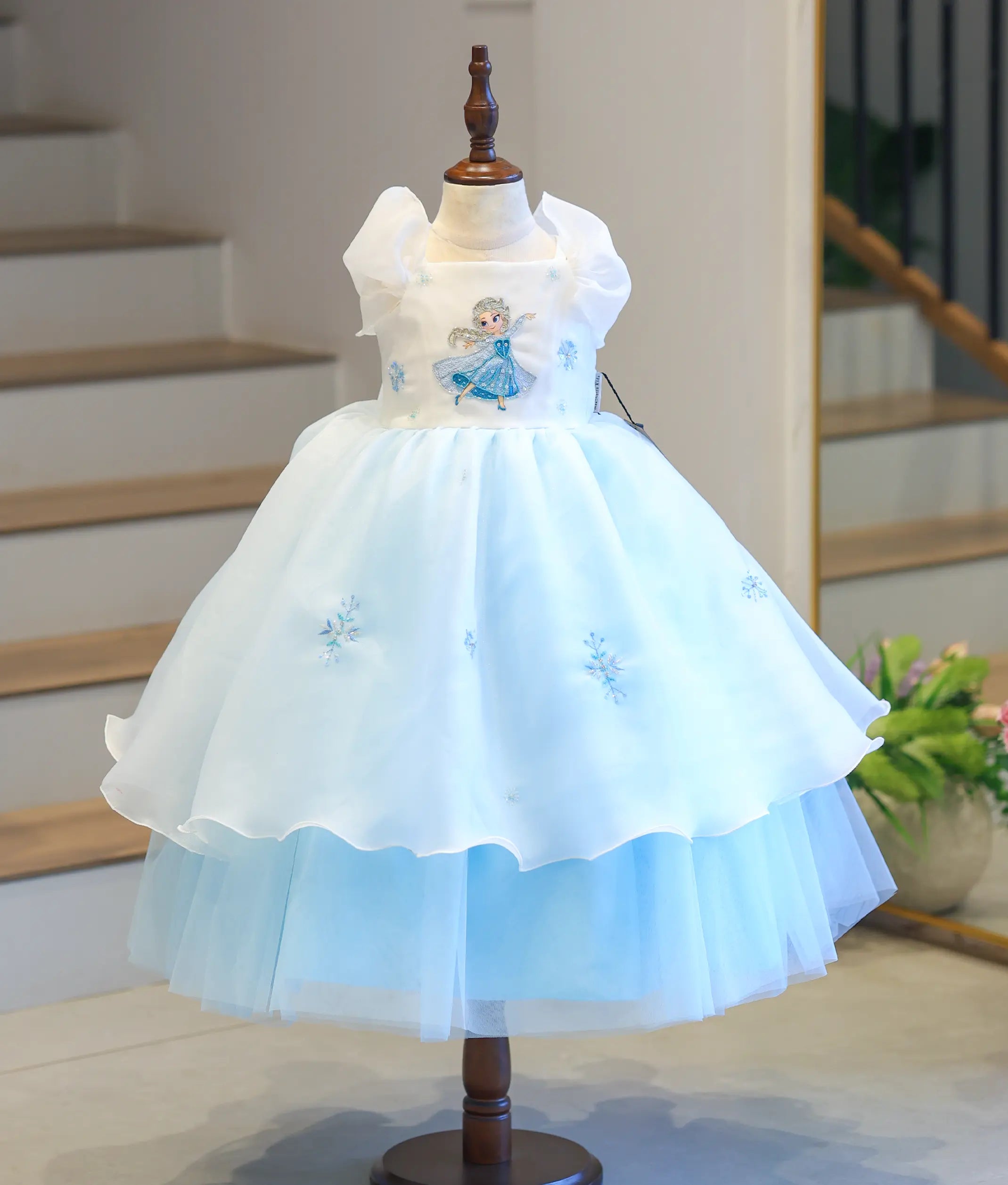 Full front view of a premium kids' ice blue and off-white Frozen Elsa theme party dress on a mannequin, showcasing the tiered organza and net skirt.