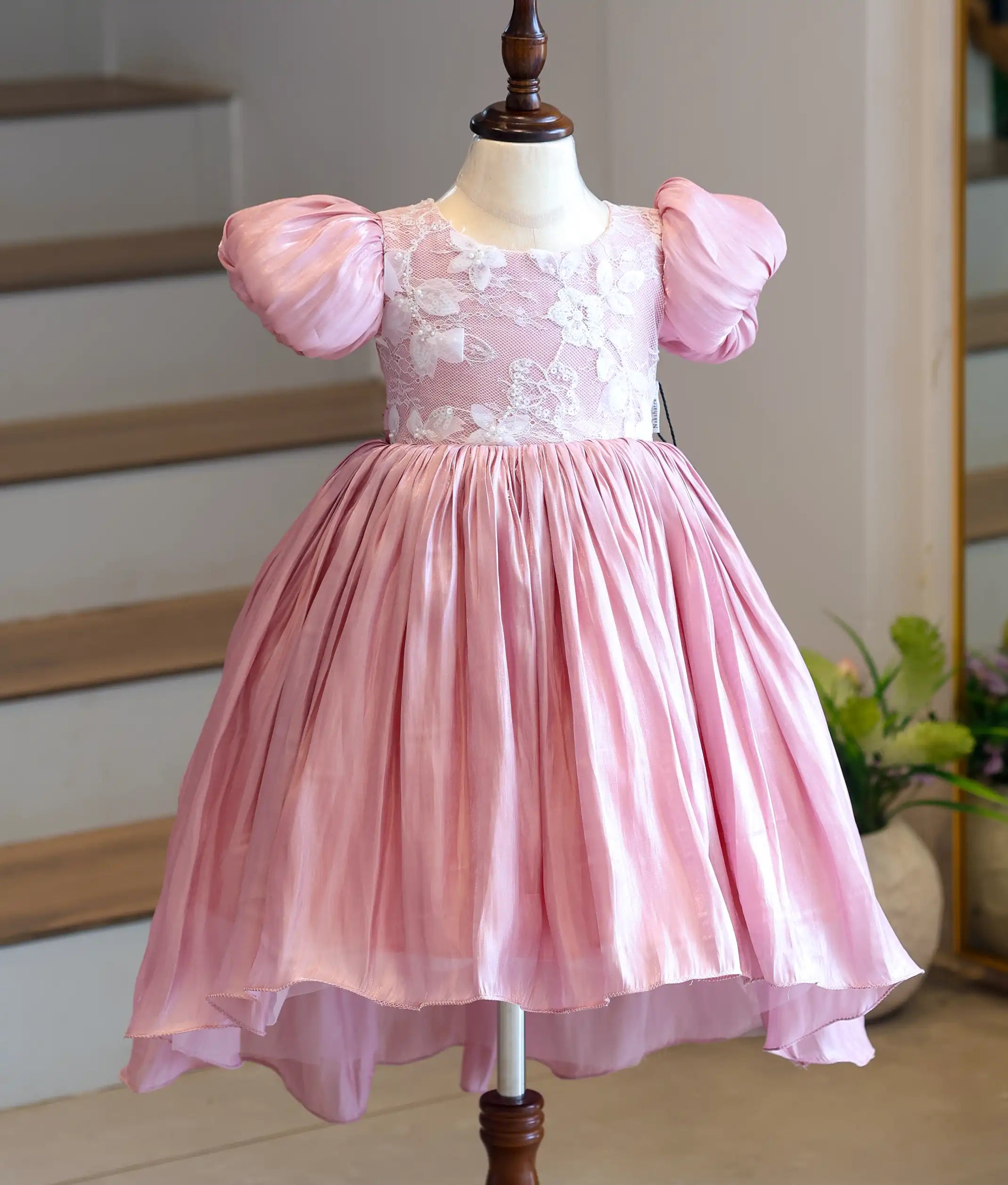 Full front view of a premium kids' onion pink high-low frock on a mannequin, showcasing the embroidered work top and cascading laser organza skirt.