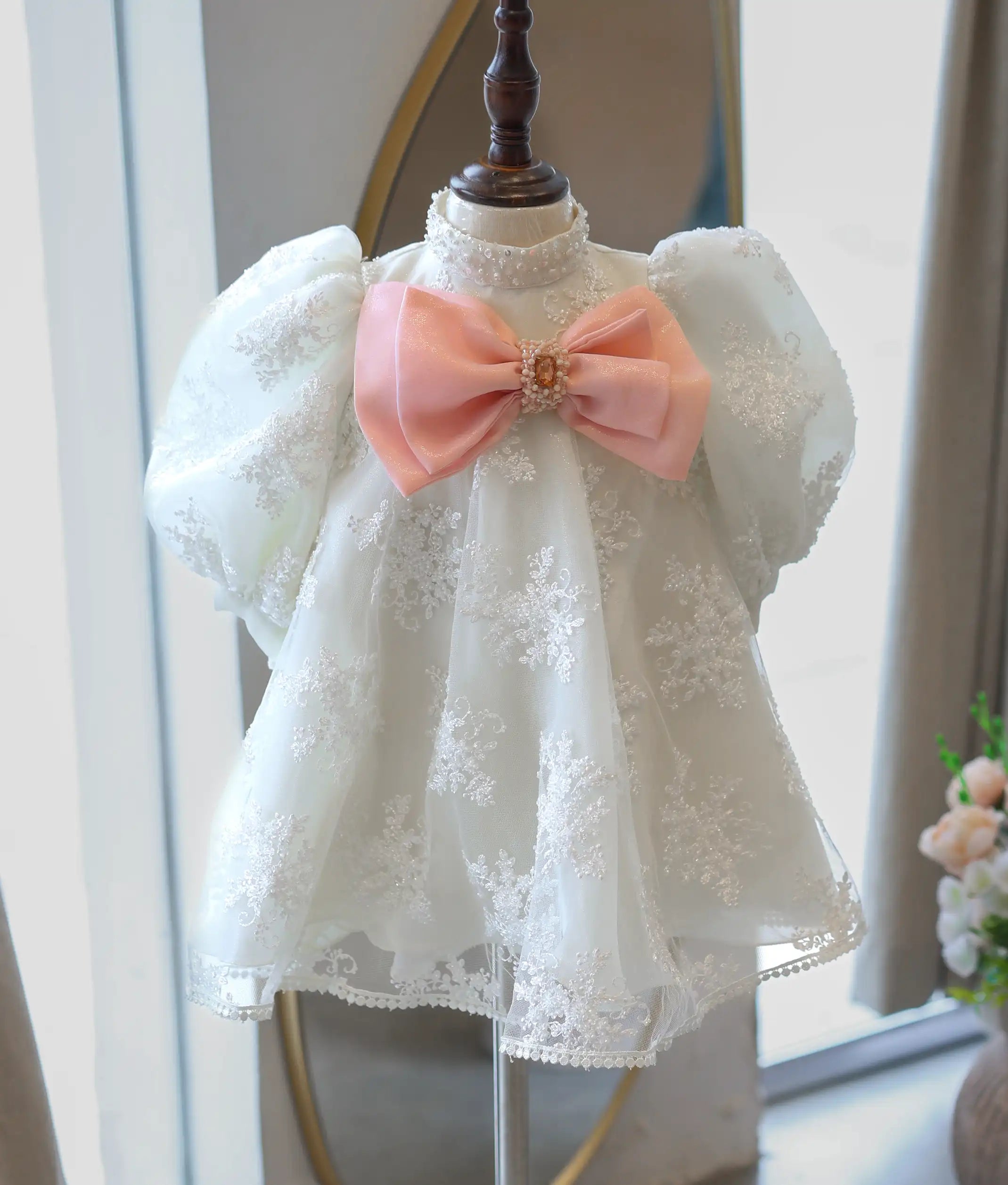 Full front view of the premium off-white embroidered net kids' party frock on a mannequin, showing its high collar, puff sleeves, and pink accent bow.