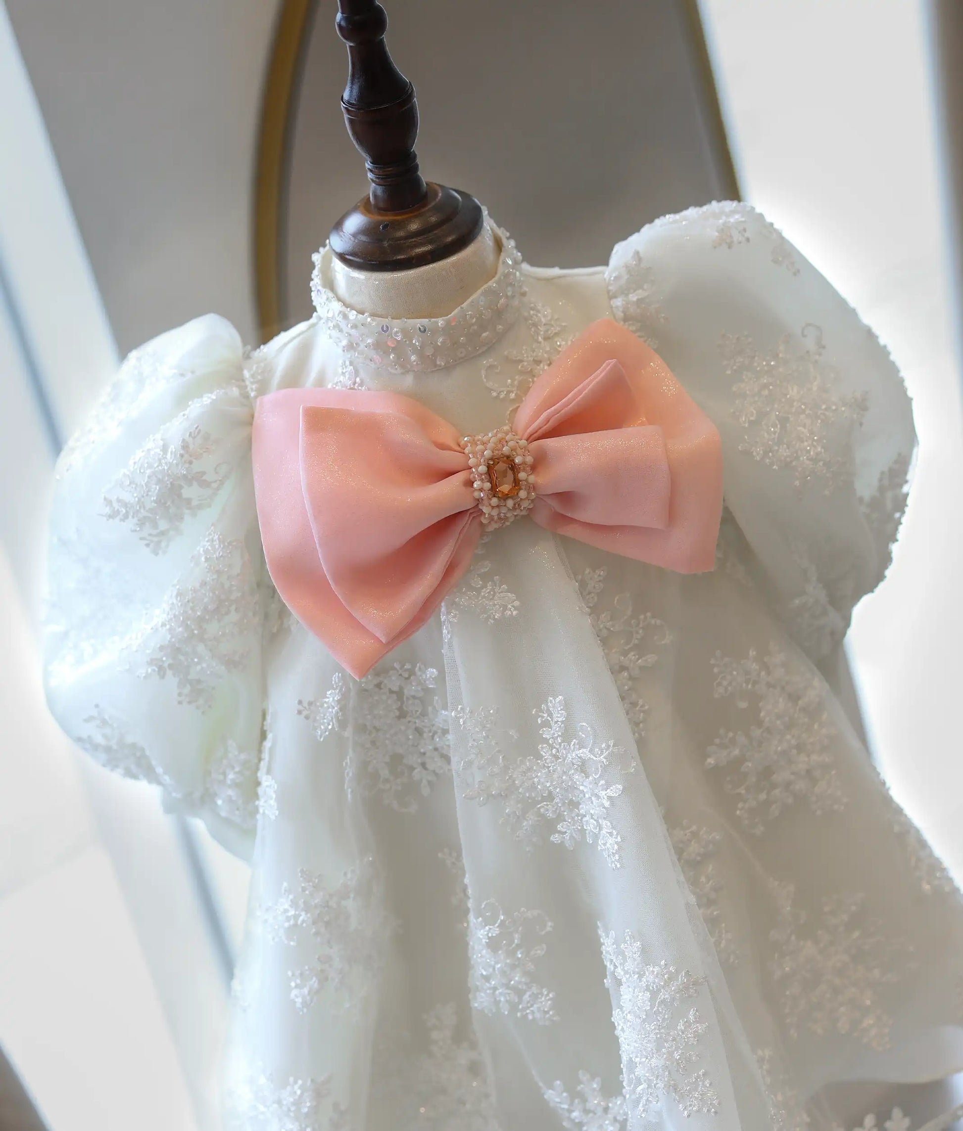A close-up view of the dress top, highlighting the hand-beaded pearl high collar and the oversized pink organza bow with its sparkling crystal center.