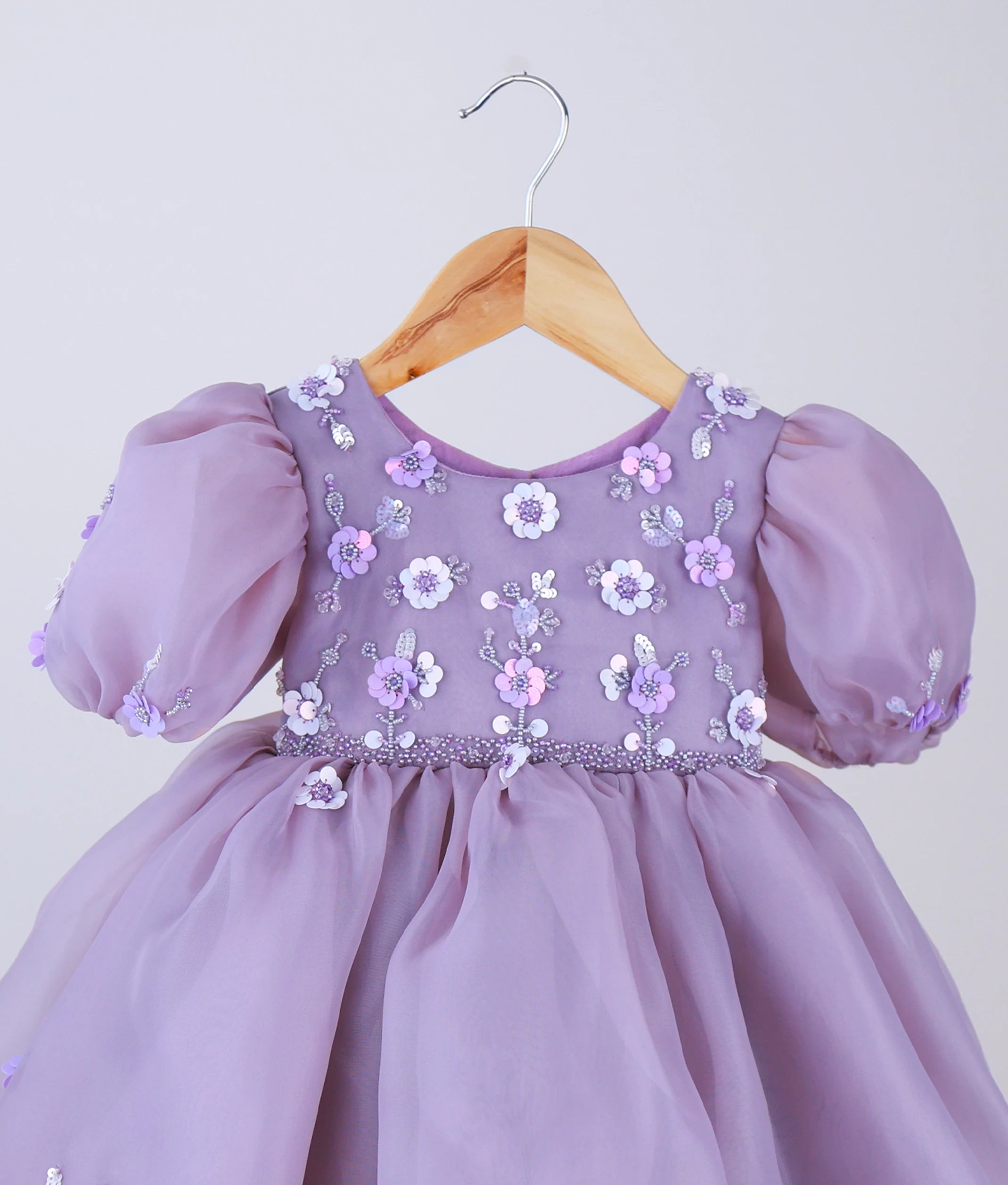 Close-up of the pastel lavender bodice showing intricate floral embroidery, glittering sequins, and beadwork