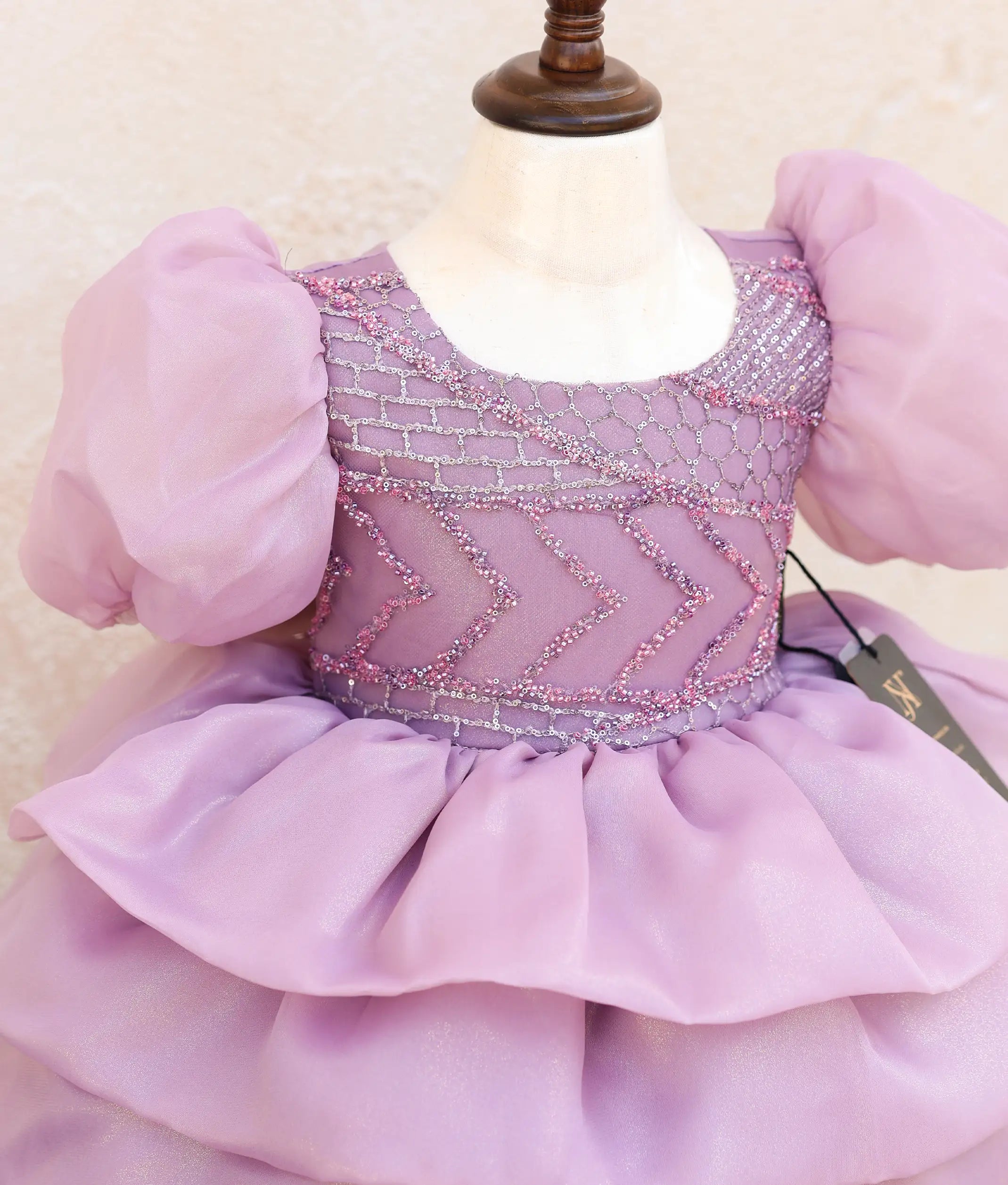 Close-up of the lavender dress showing the glittering geometric beadwork and charming melon-style sleeves