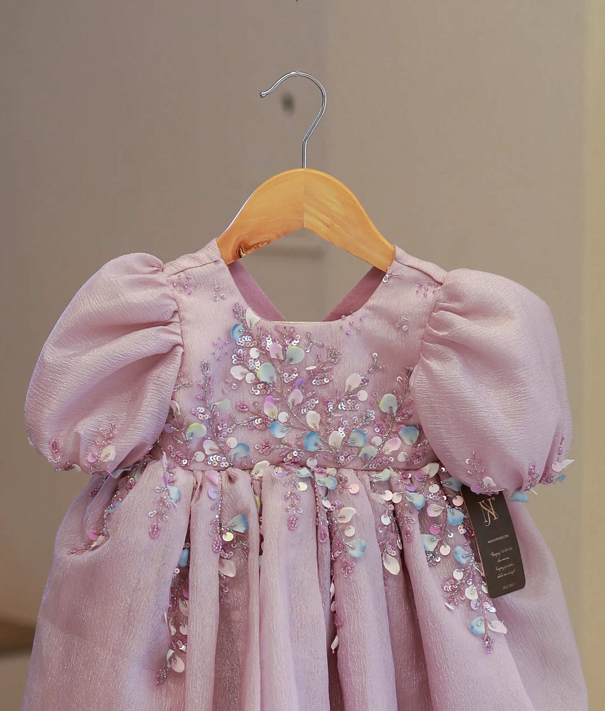 Close-up of the pastel lavender frock bodice showing intricate floral handwork, bead embellishments, and round neck