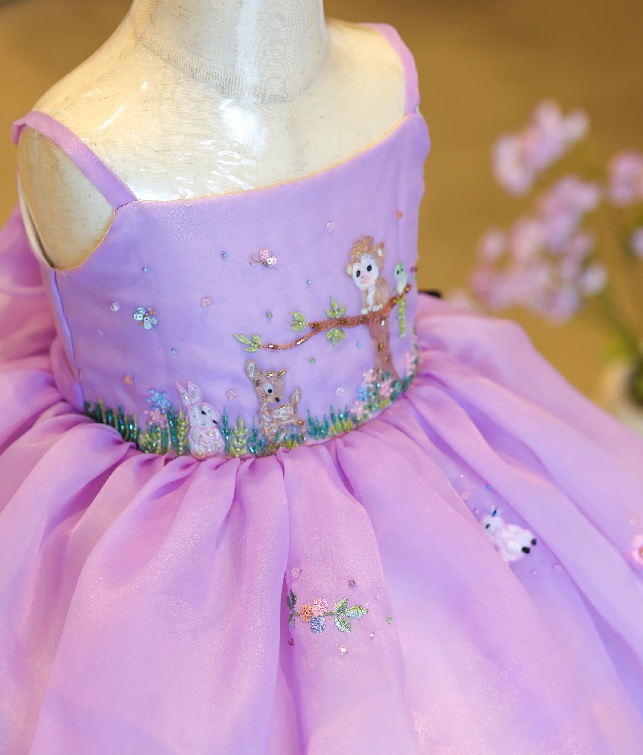 Close-up of the intricate handworked fawn motif and floral embroidery on the bodice of the lavender birthday dress