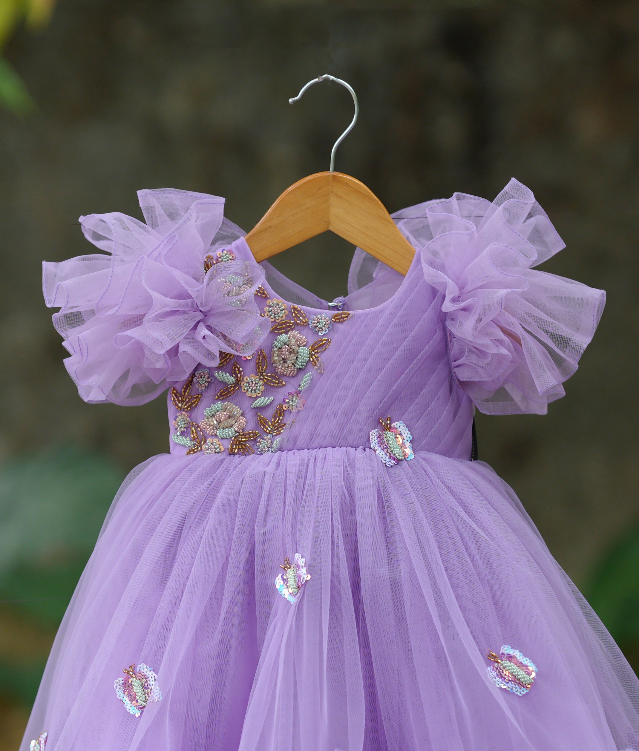 Close-up of the lavender gown yoke showing delicate floral embroidery, sequins, and the ruffled sleeve detail