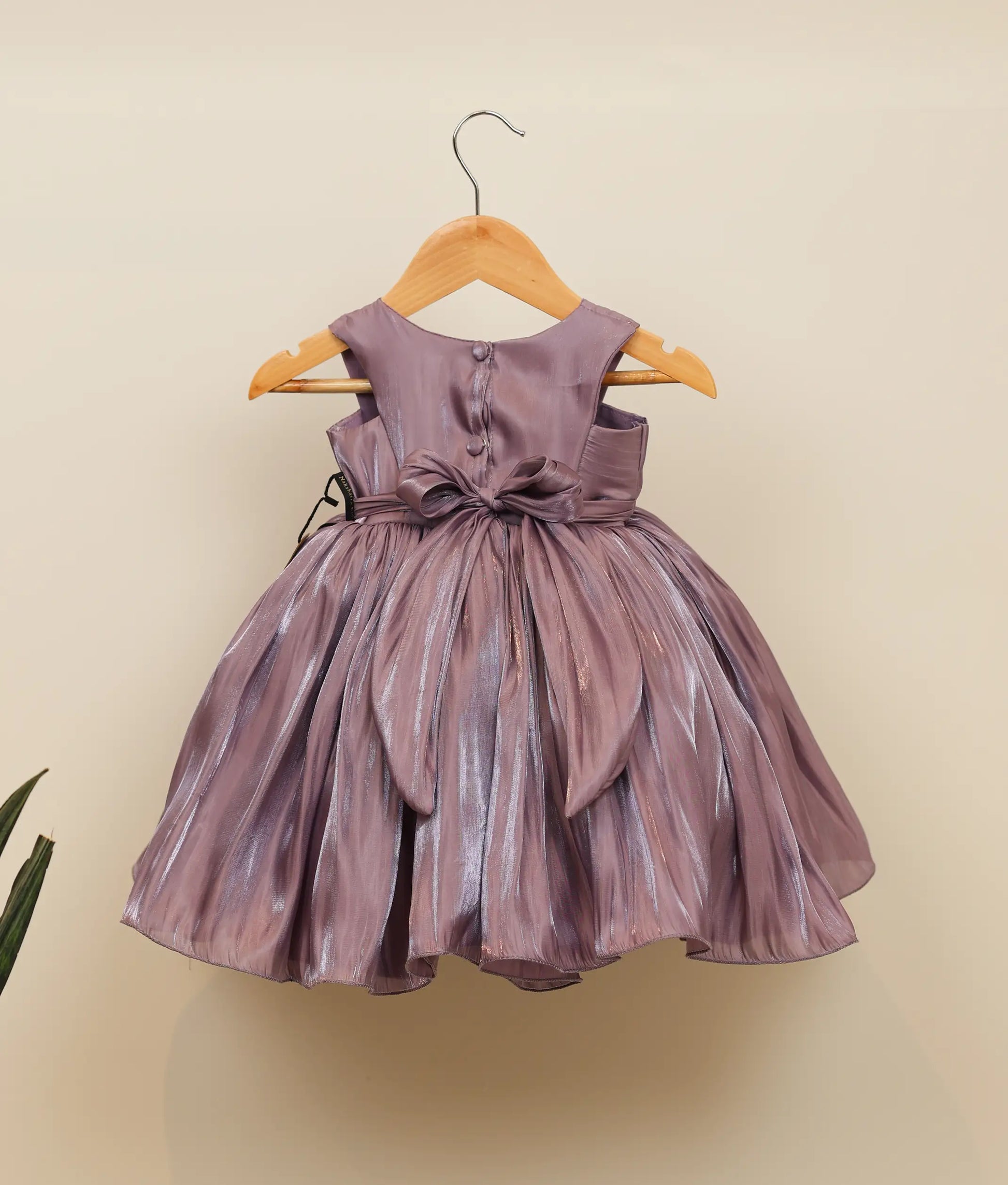 Back view of lavender laser organza frock showing the round neckline with show button, back tie, and full gathered skirt