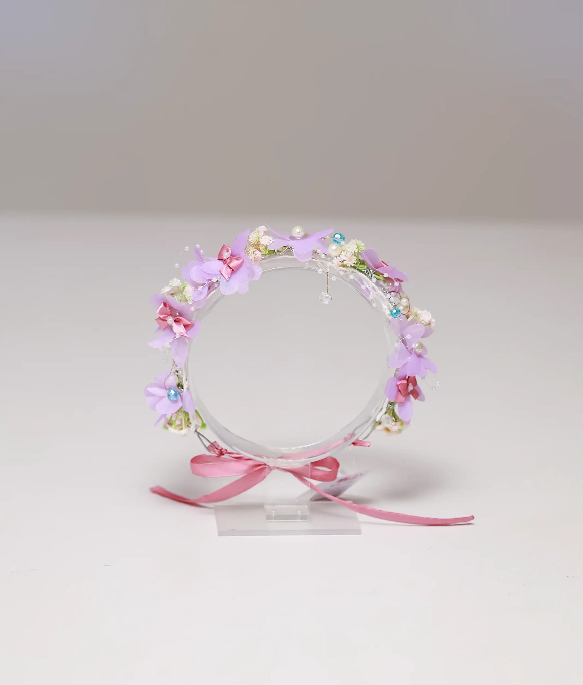 Front view of a lavender and pink floral handmade tiara for girls with pearls and ribbon tie