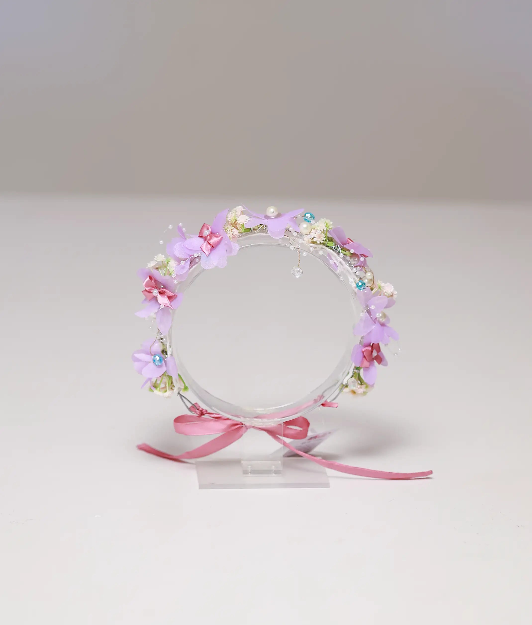 Front view of a lavender and pink floral handmade tiara for girls with pearls and ribbon tie