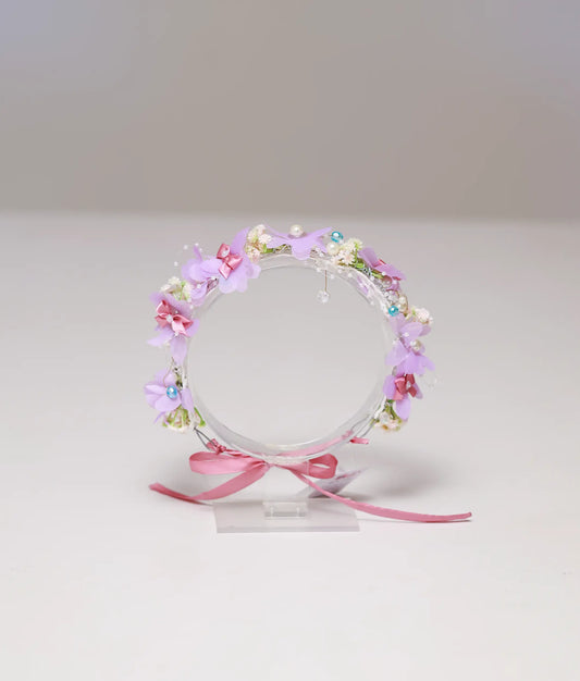 Front view of a lavender and pink floral handmade tiara for girls with pearls and ribbon tie