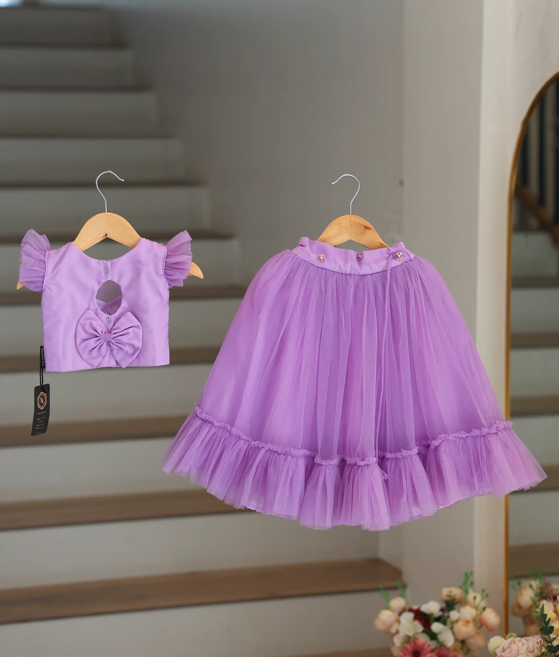 Back view of the lavender crop top and skirt showing the keyhole button closure and decorative bow