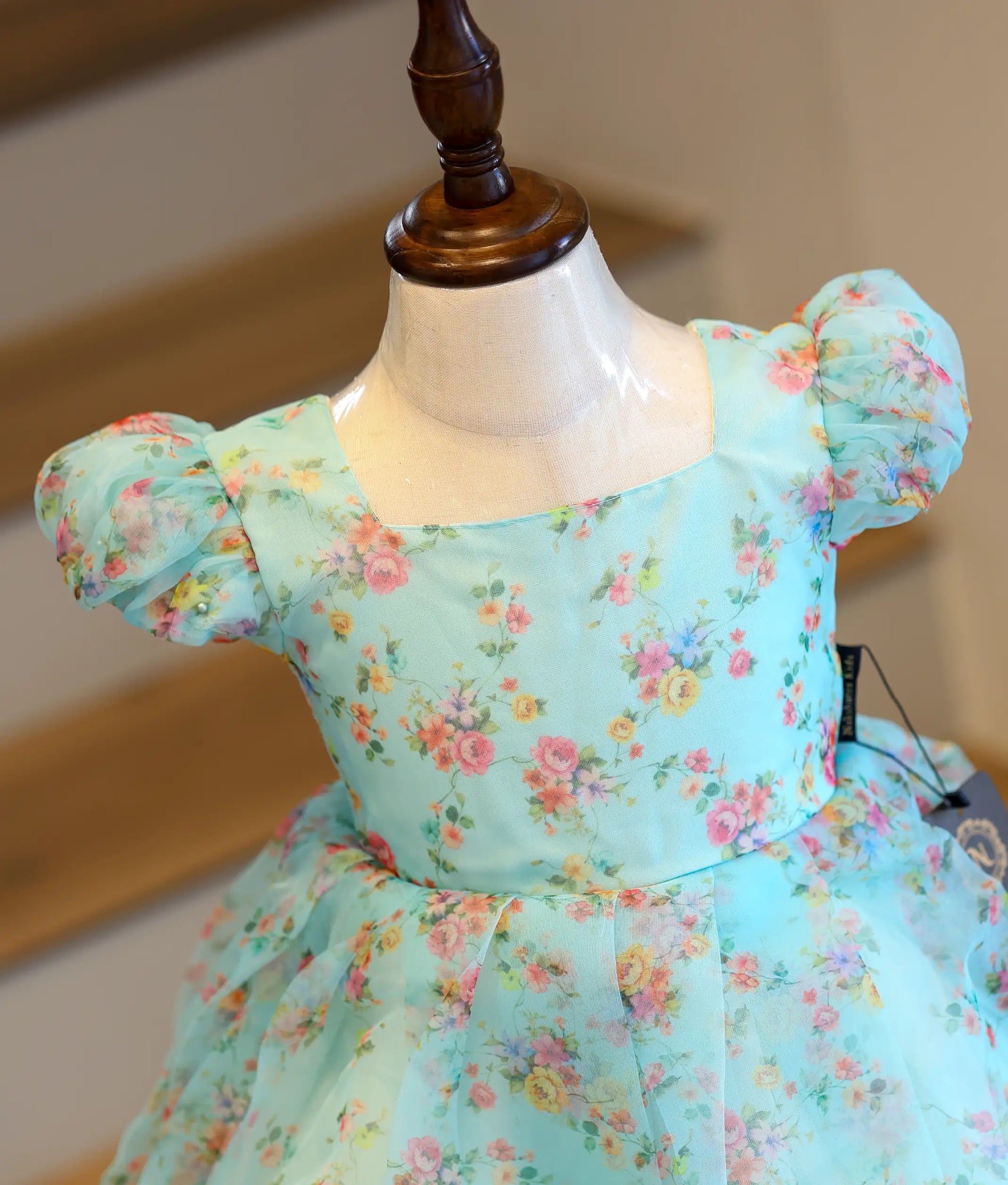Close-up view of the delicate floral print and short puff sleeves on the light blue organza casual frock