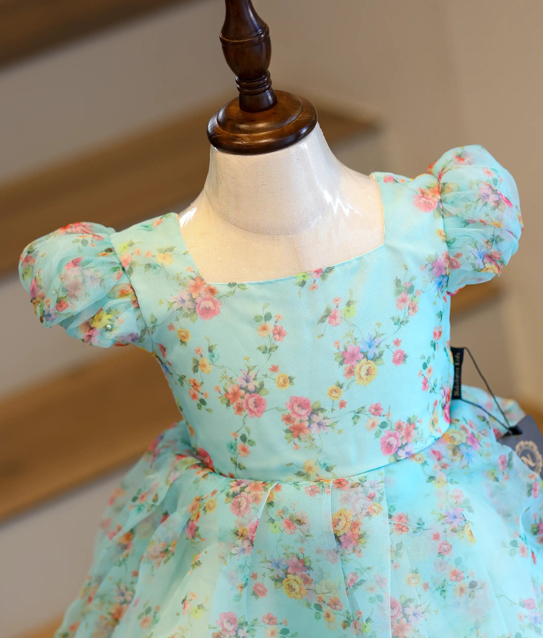 Close-up view of the delicate floral print and short puff sleeves on the light blue organza casual frock