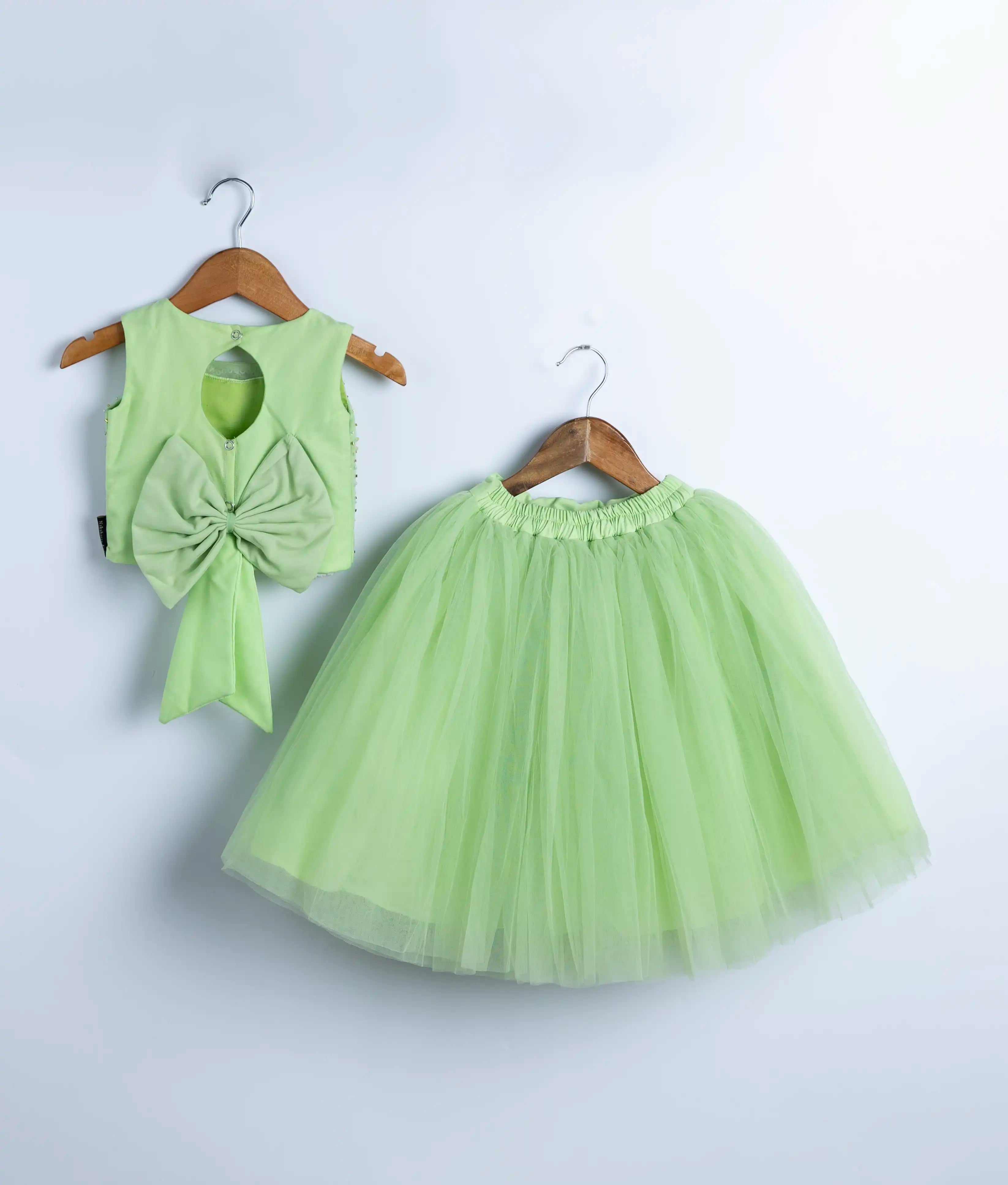 Flat lay of baby girl skirt and top in light green with handmade embroidery and tulle detailing