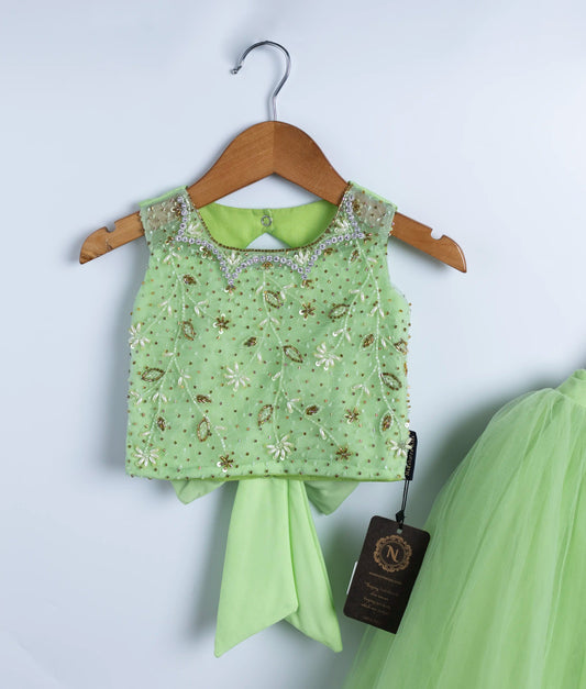 Close-up of light green baby girl top with handmade floral embroidery and cap sleeves