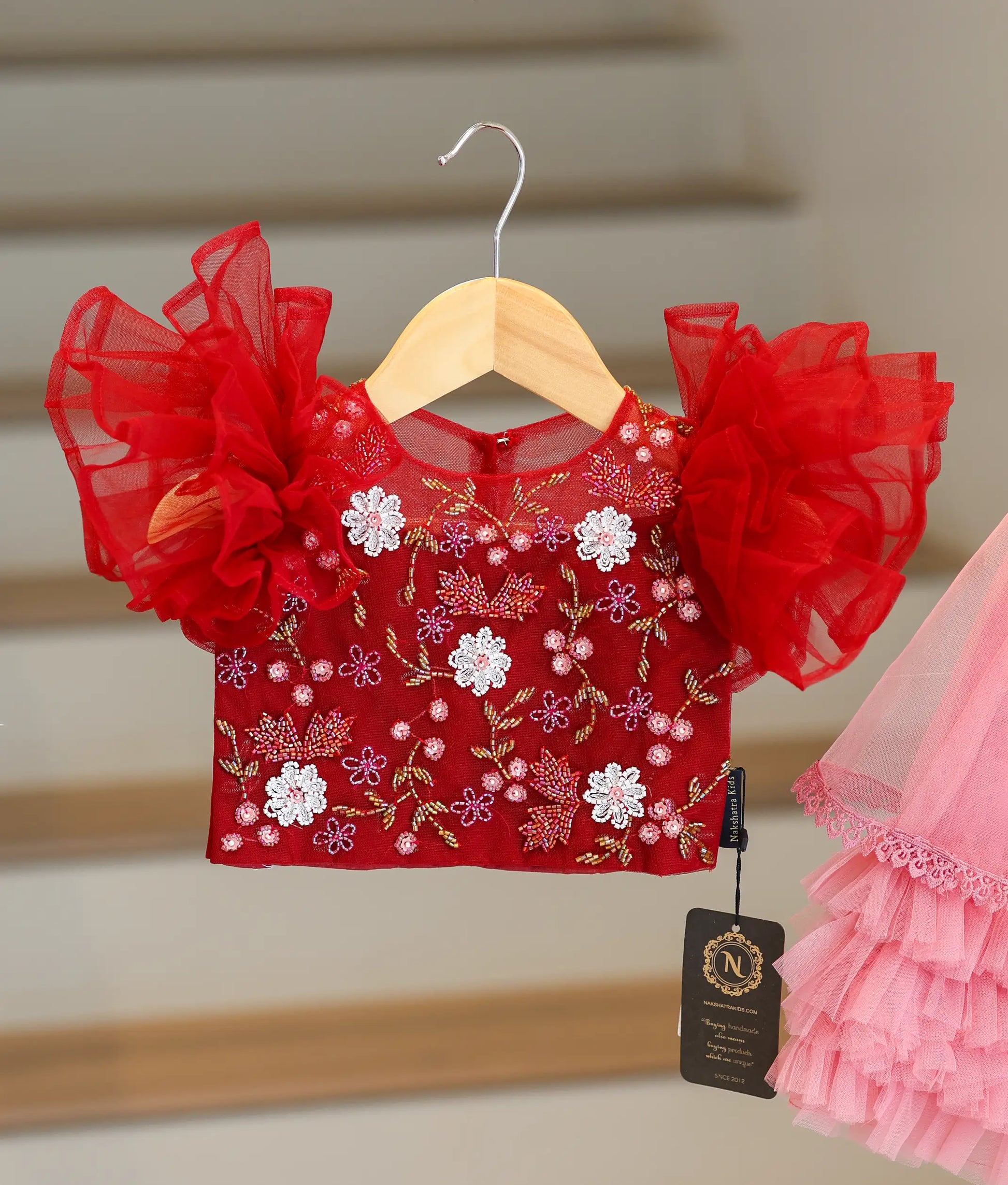 Close-up of the maroon top showing the colorful floral beadwork and pretty ruffled sleeves
