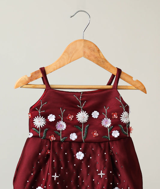 Close-up view of the yoke on the maroon festive dress, showcasing the detailed pink and white bead floral embroidery.