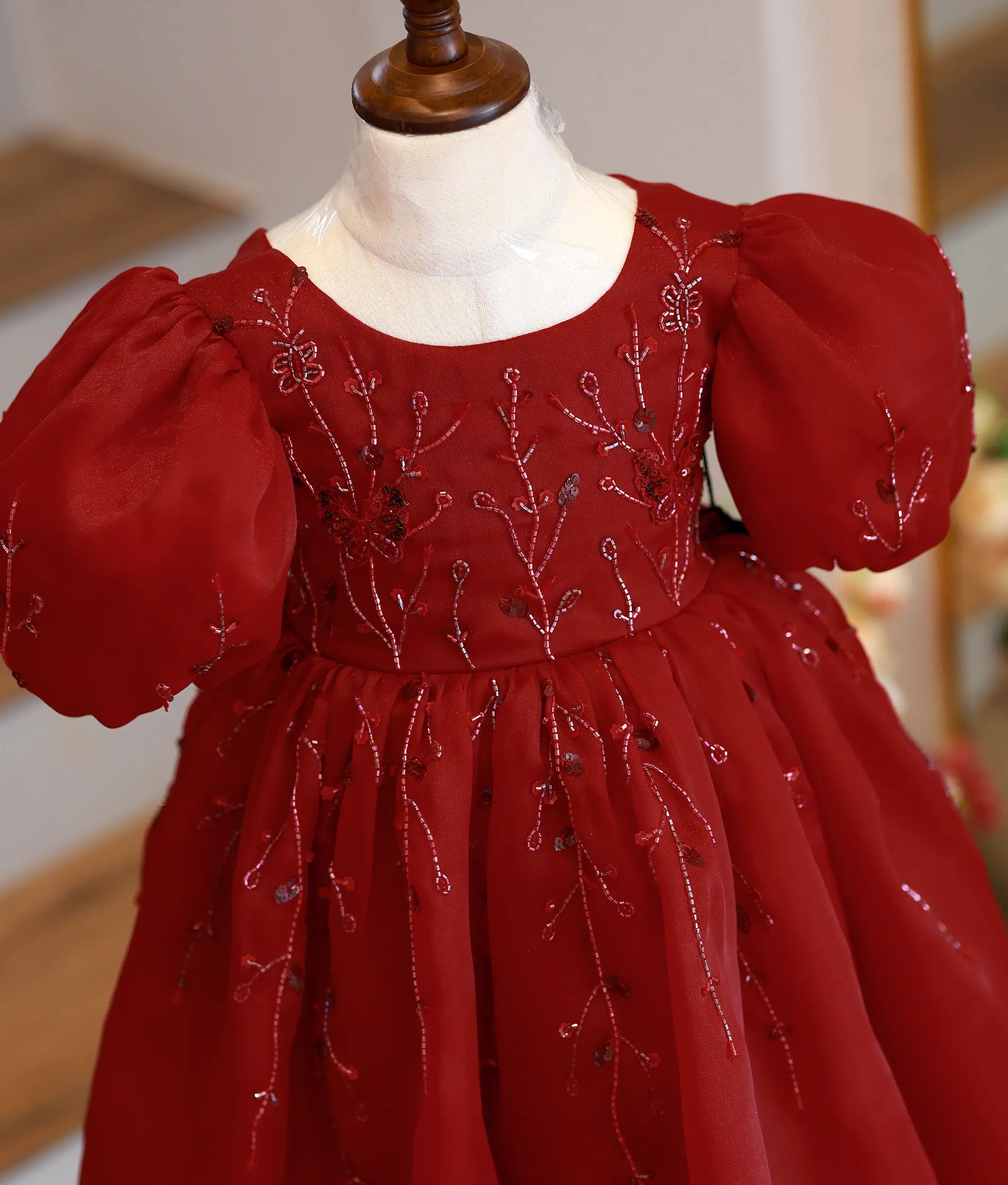 Close-up of the maroon gown showing intricate bead and sequin handwork and butterfly applique detailing
