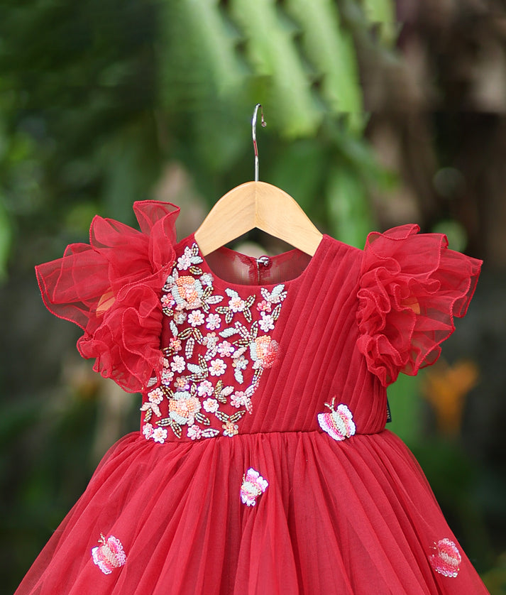 Close-up of the maroon gown yoke showing delicate floral embroidery, sequins, and the ruffled sleeve detail