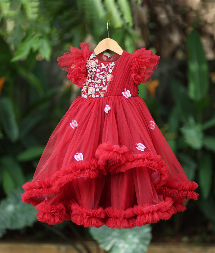 Front view of a maroon butterfly theme birthday gown with floral handwork and a voluminous frilled skirt